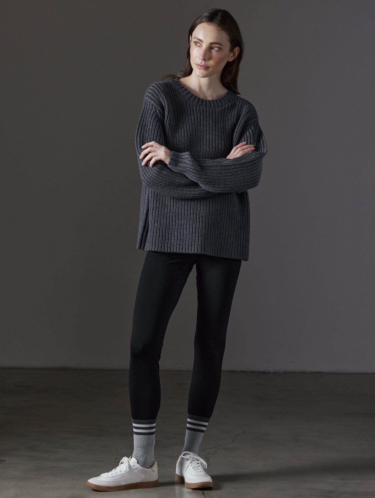 Front full-body view of woman wearing Sherwood Crewneck Sweater in Dark Grey Heather from AETHER Apparel.