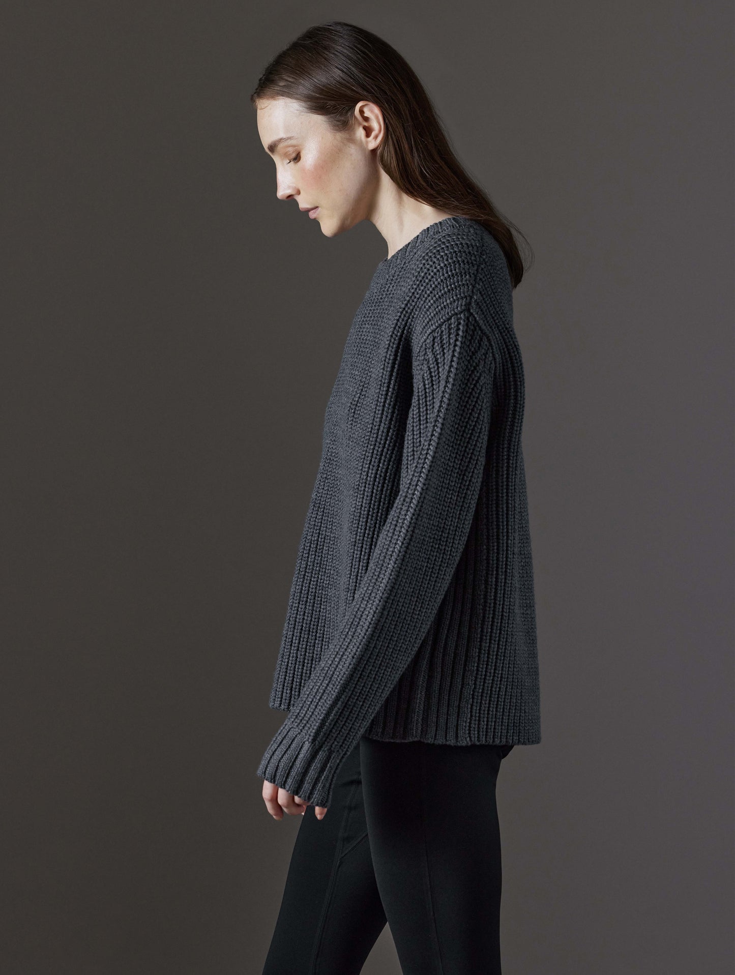 Side profile view of woman wearing Sherwood Crewneck Sweater in Dark Grey Heather from AETHER Apparel.