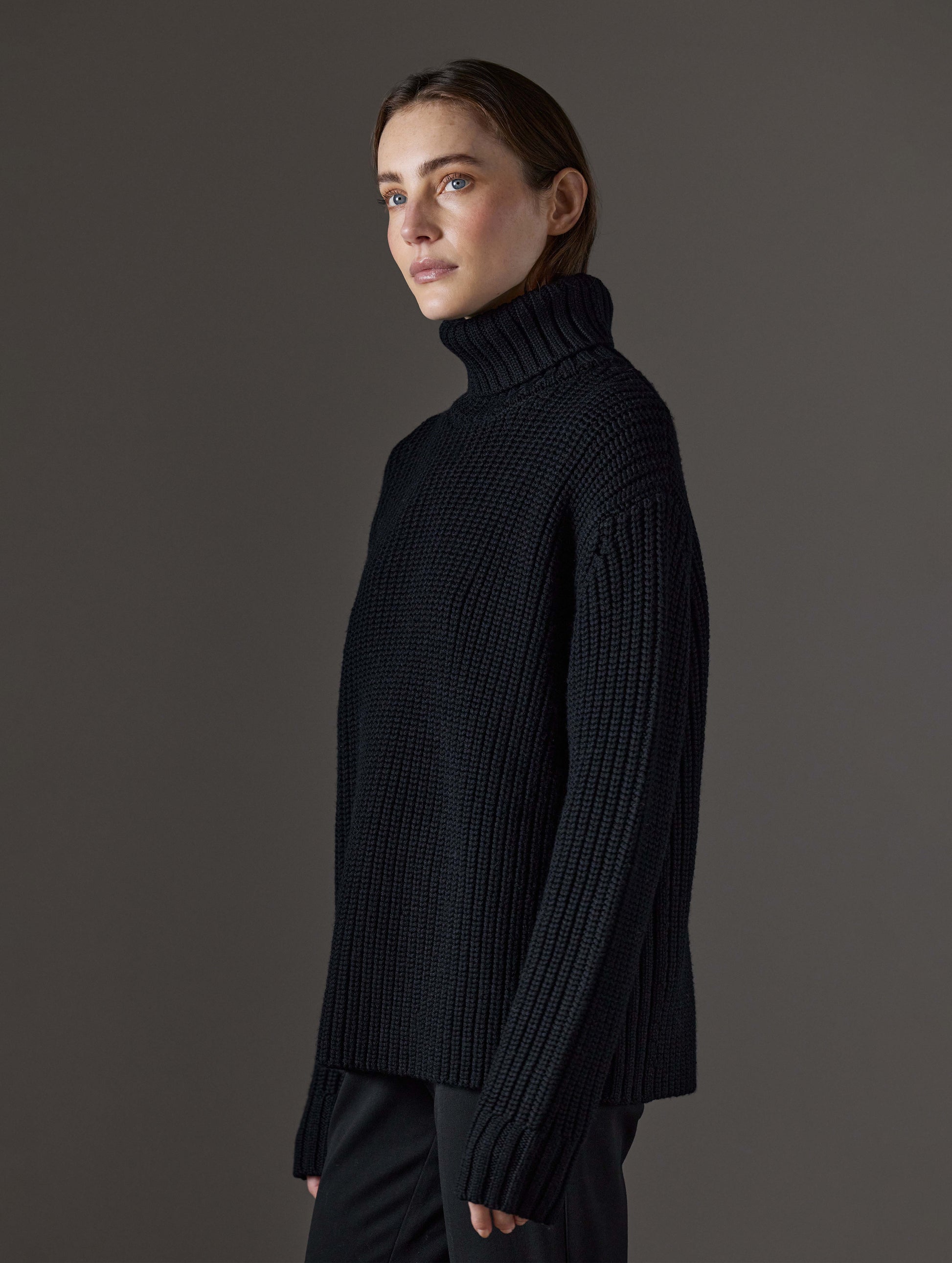 Side profile view of woman wearing Sherwood Turtleneck Sweater in Onyx Black from AETHER Apparel.