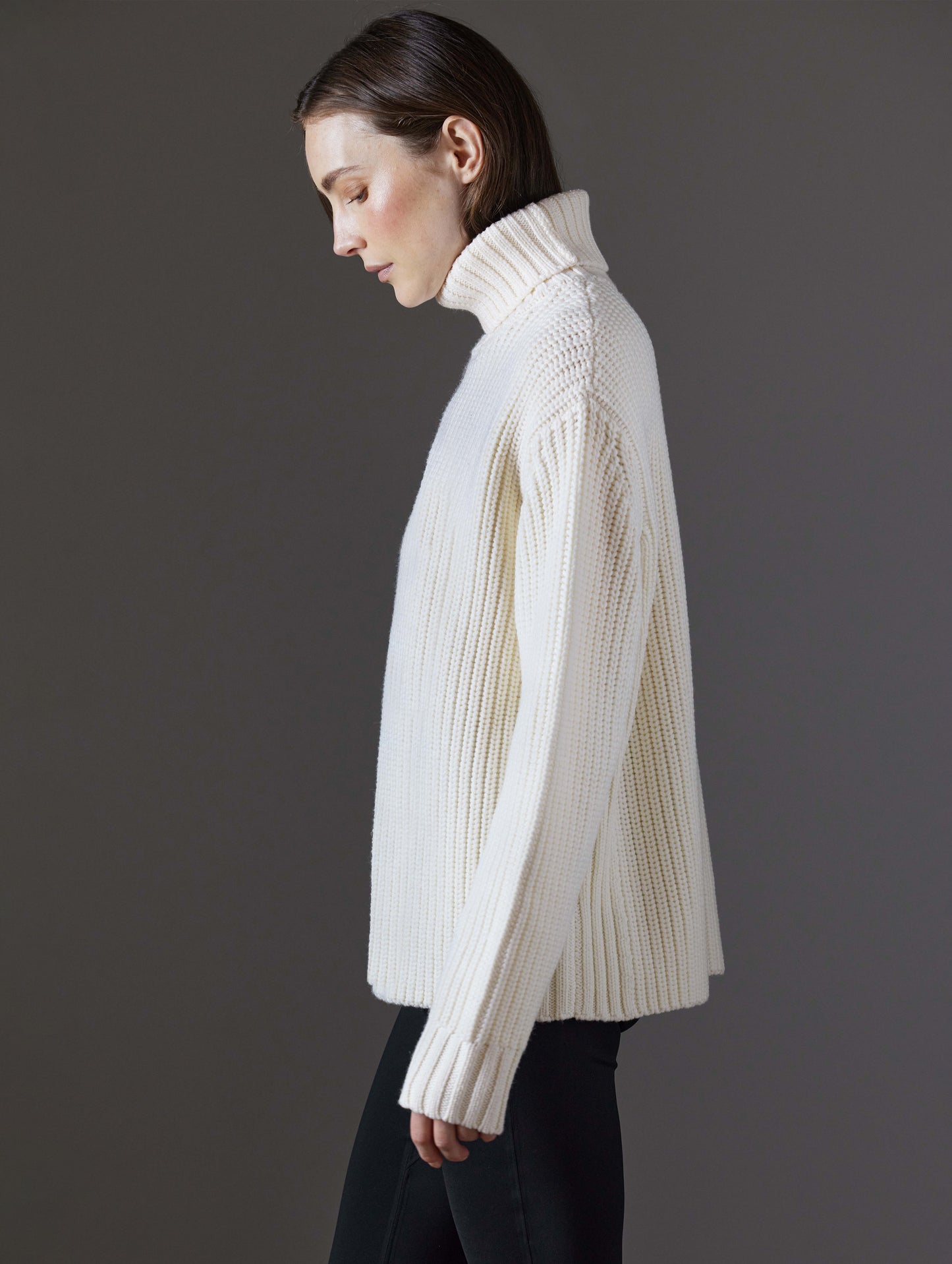 Side profile view of woman wearing Sherwood Turtleneck Sweater in Winter White from AETHER Apparel.