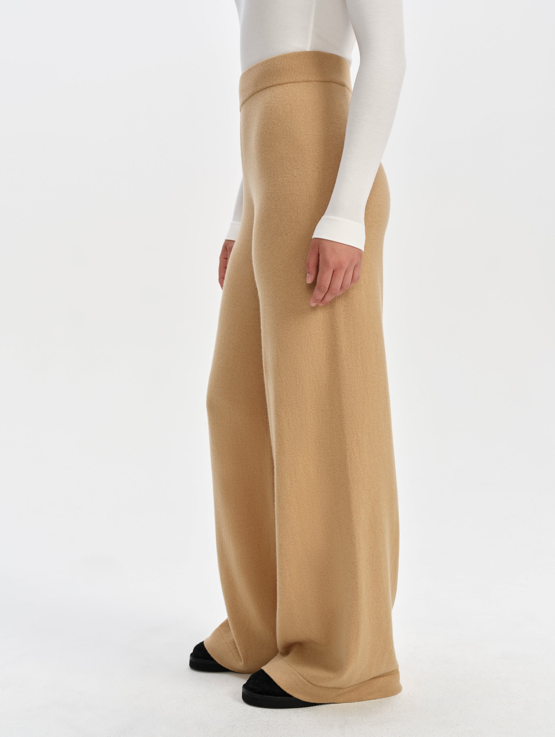 Side profile lower-body view of woman wearing the Solace Cashmere Pant in Latte Brown from AETHER Apparel.