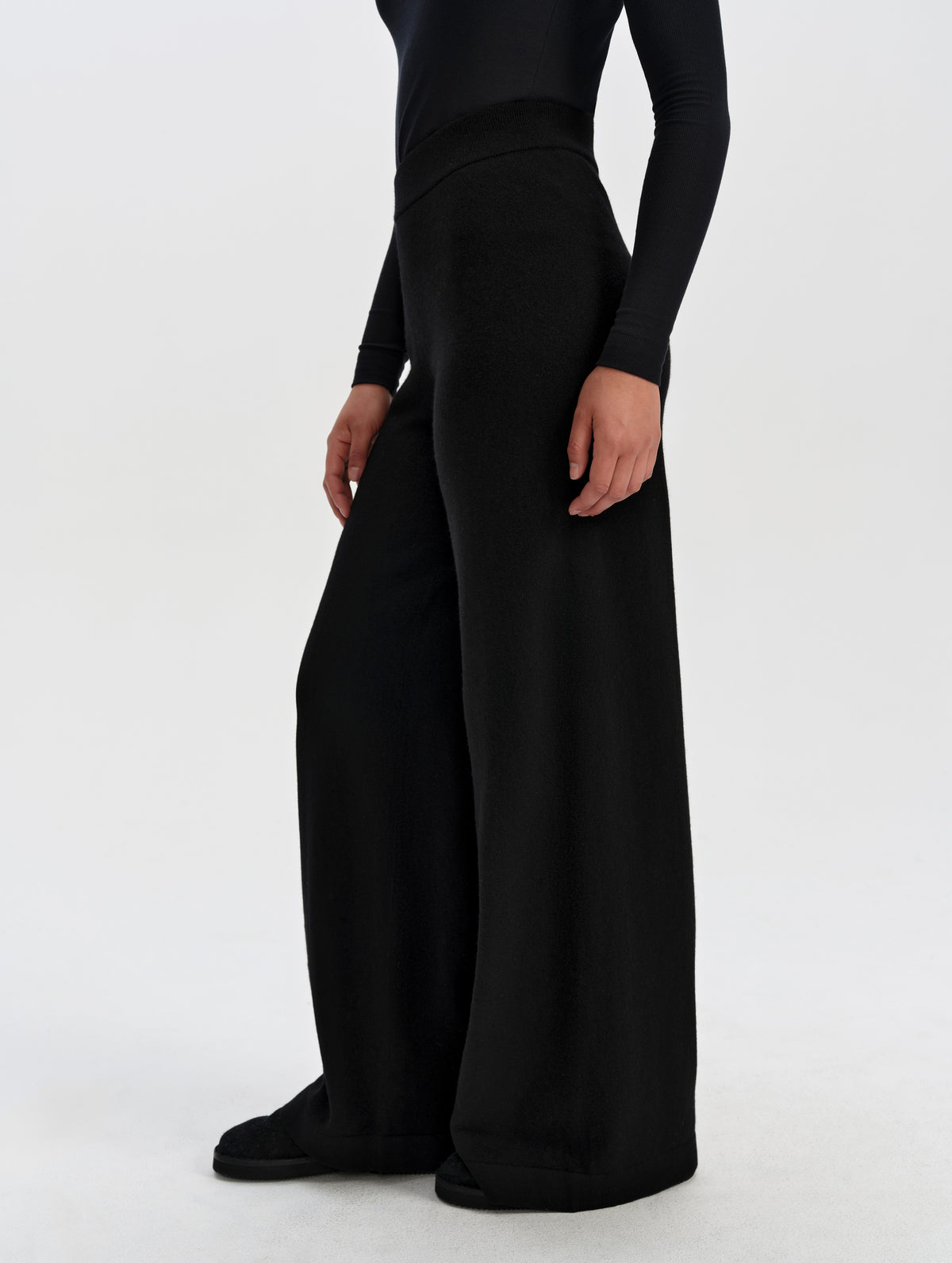 Side profile lower-body view of woman wearing the Solace Cashmere Pant in Onyx Black from AETHER Apparel.