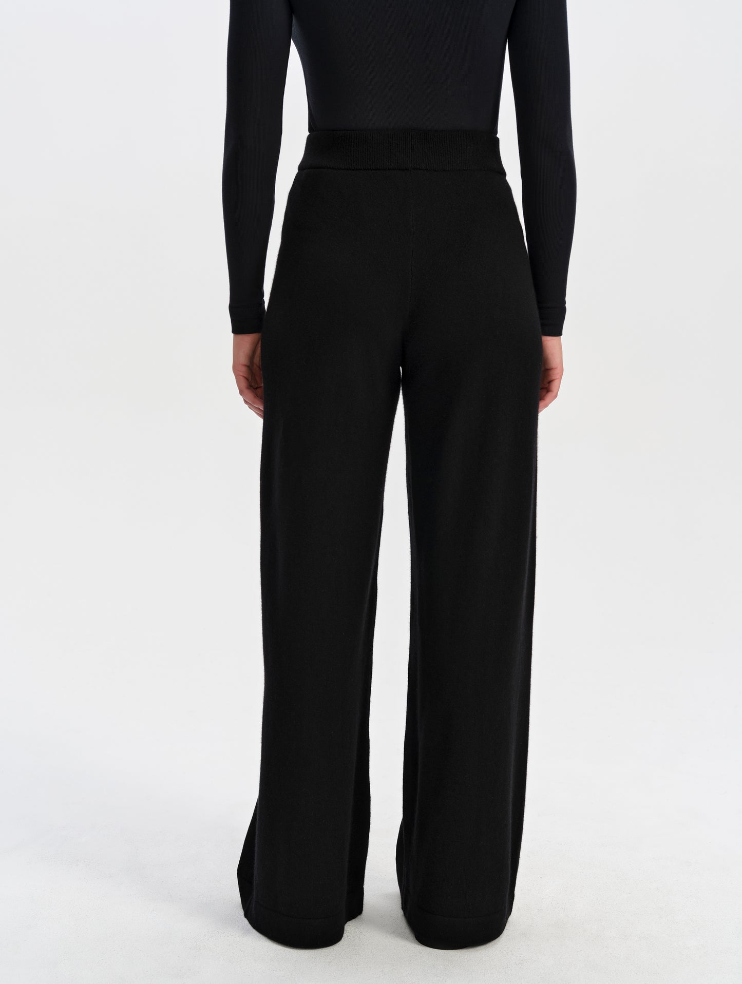 Rear lower-body view of woman wearing the Solace Cashmere Pant in Onyx Black from AETHER Apparel.