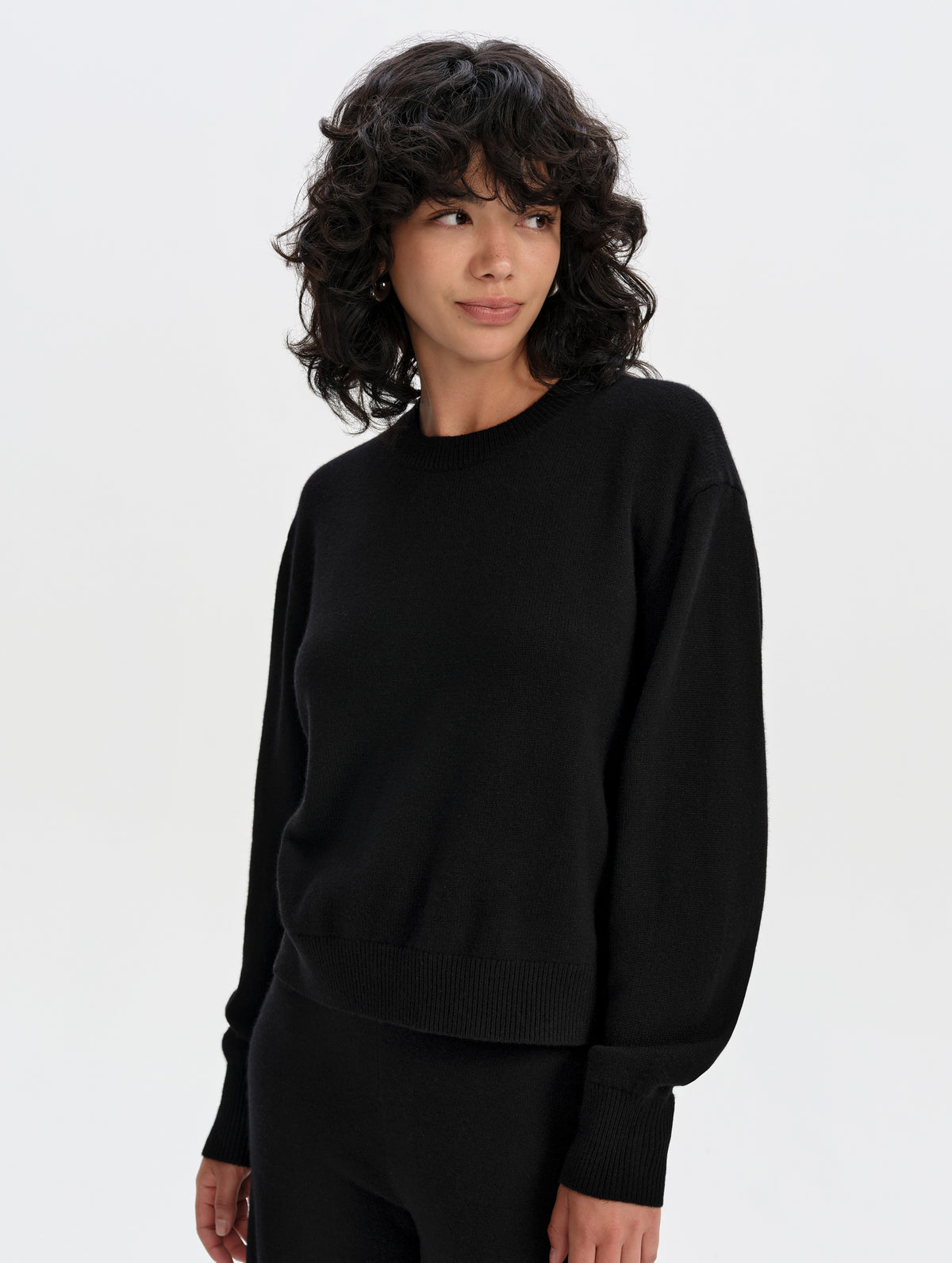Front upper-body view of woman wearing the Solace Cashmere Sweater in Onyx Black from AETHER Apparel.