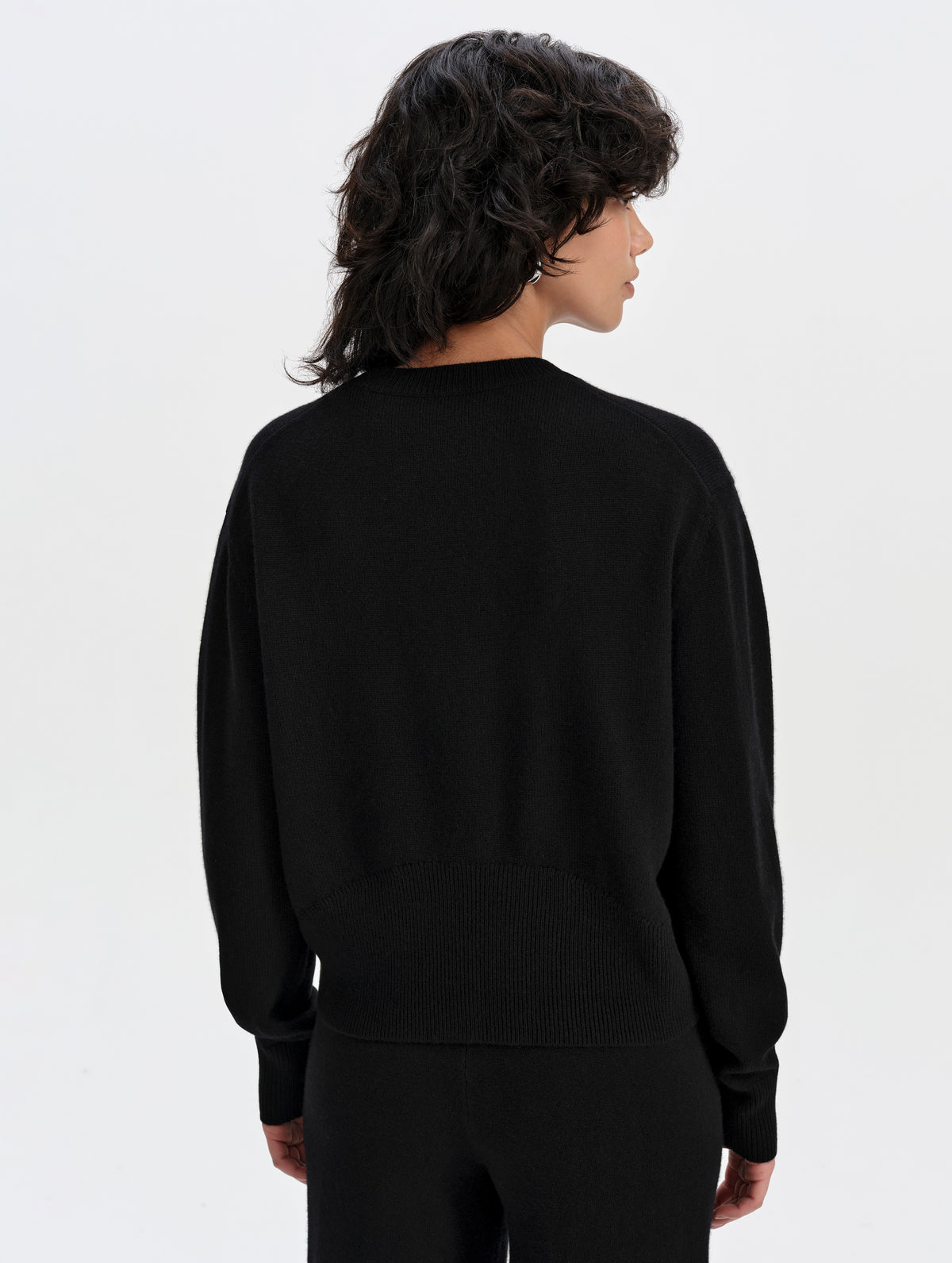 Rear upper-body view of woman wearing the Solace Cashmere Sweater in Onyx Black from AETHER Apparel.