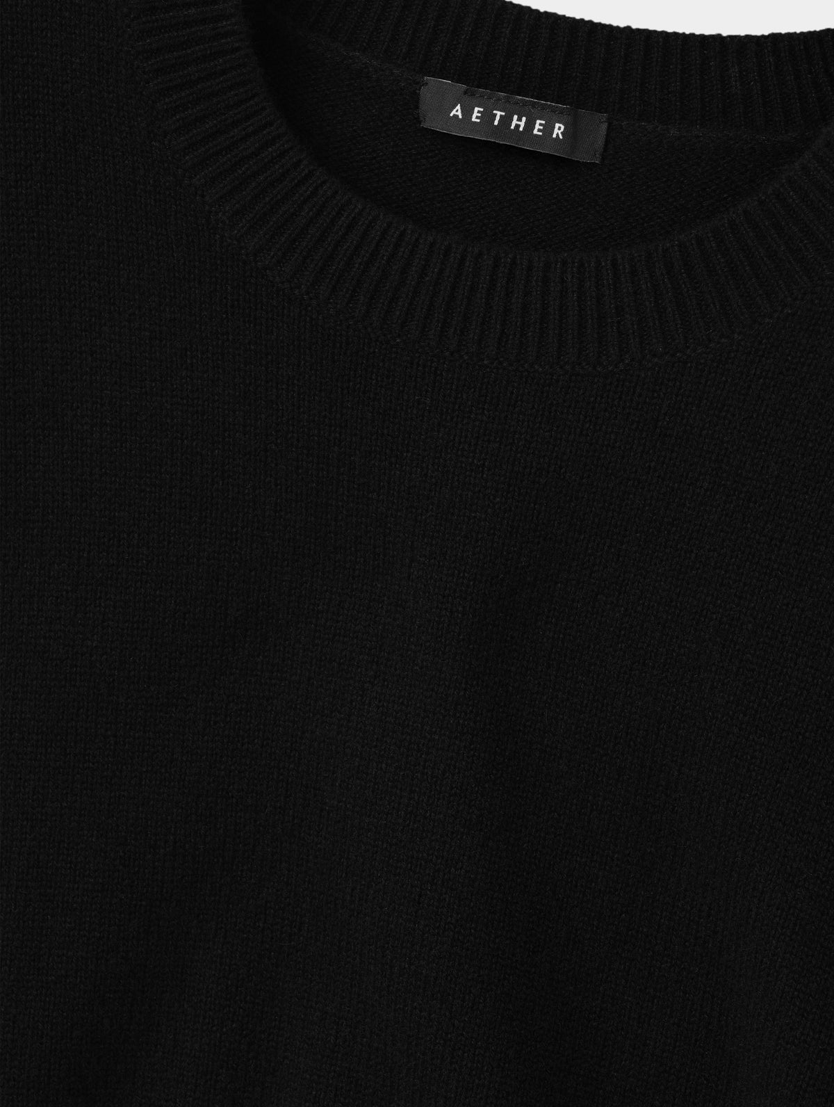 Closeup detailed view of the rib-knit collar and main body construction on the Solace Cashmere Sweater in Onyx Black from AETHER Apparel.