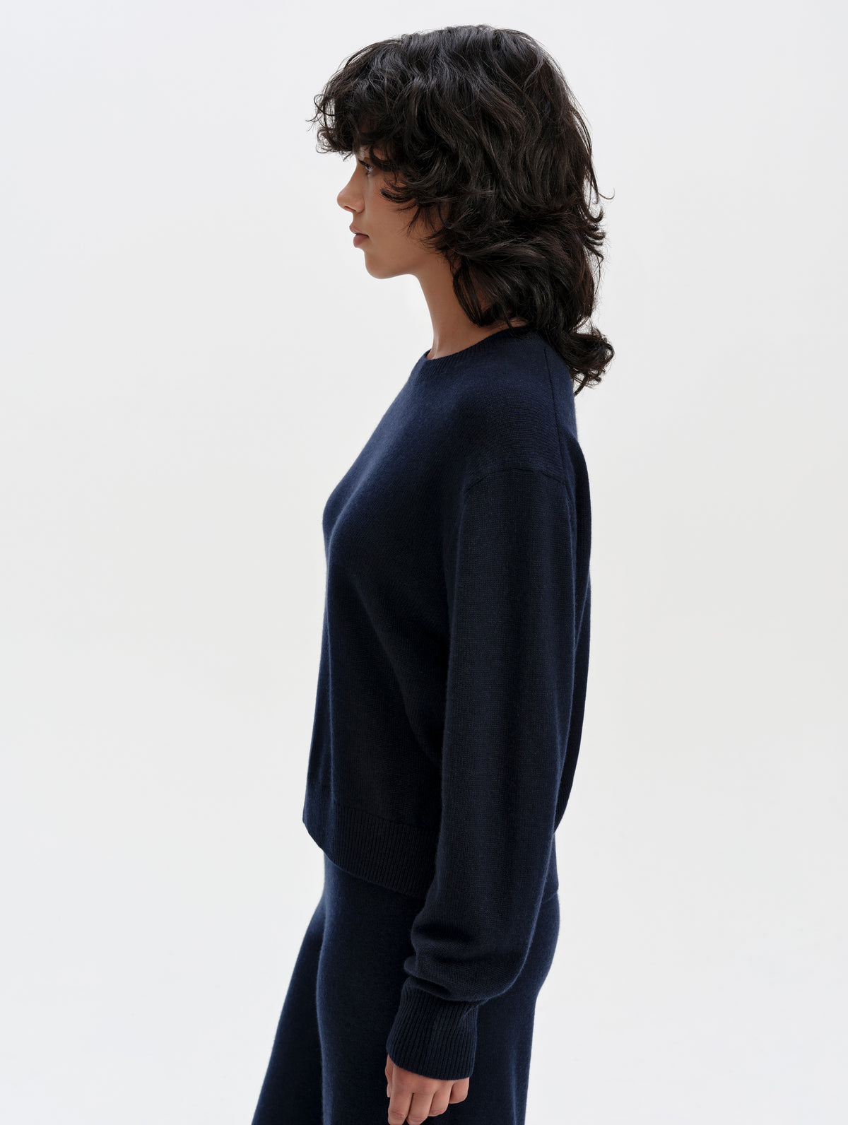 Side profile upper-body view of woman wearing the Solace Cashmere Sweater in Total Eclipse from AETHER Apparel.