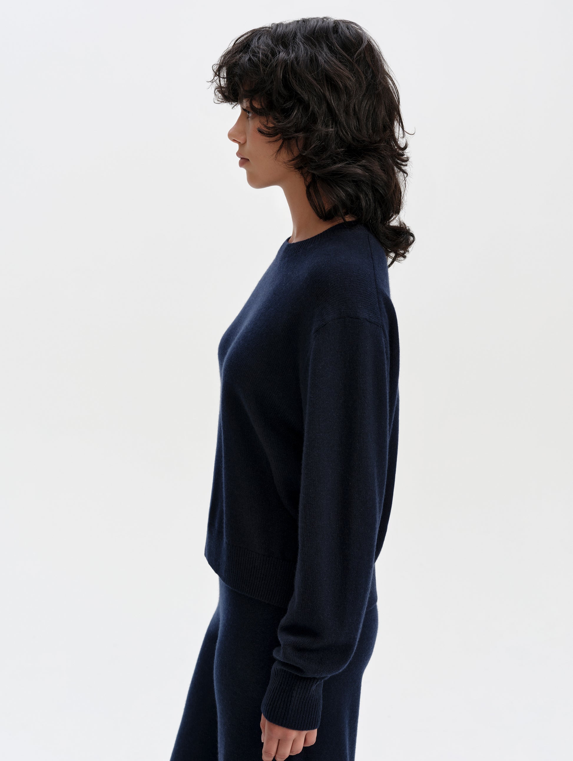 Side profile upper-body view of woman wearing the Solace Cashmere Sweater in Total Eclipse from AETHER Apparel.