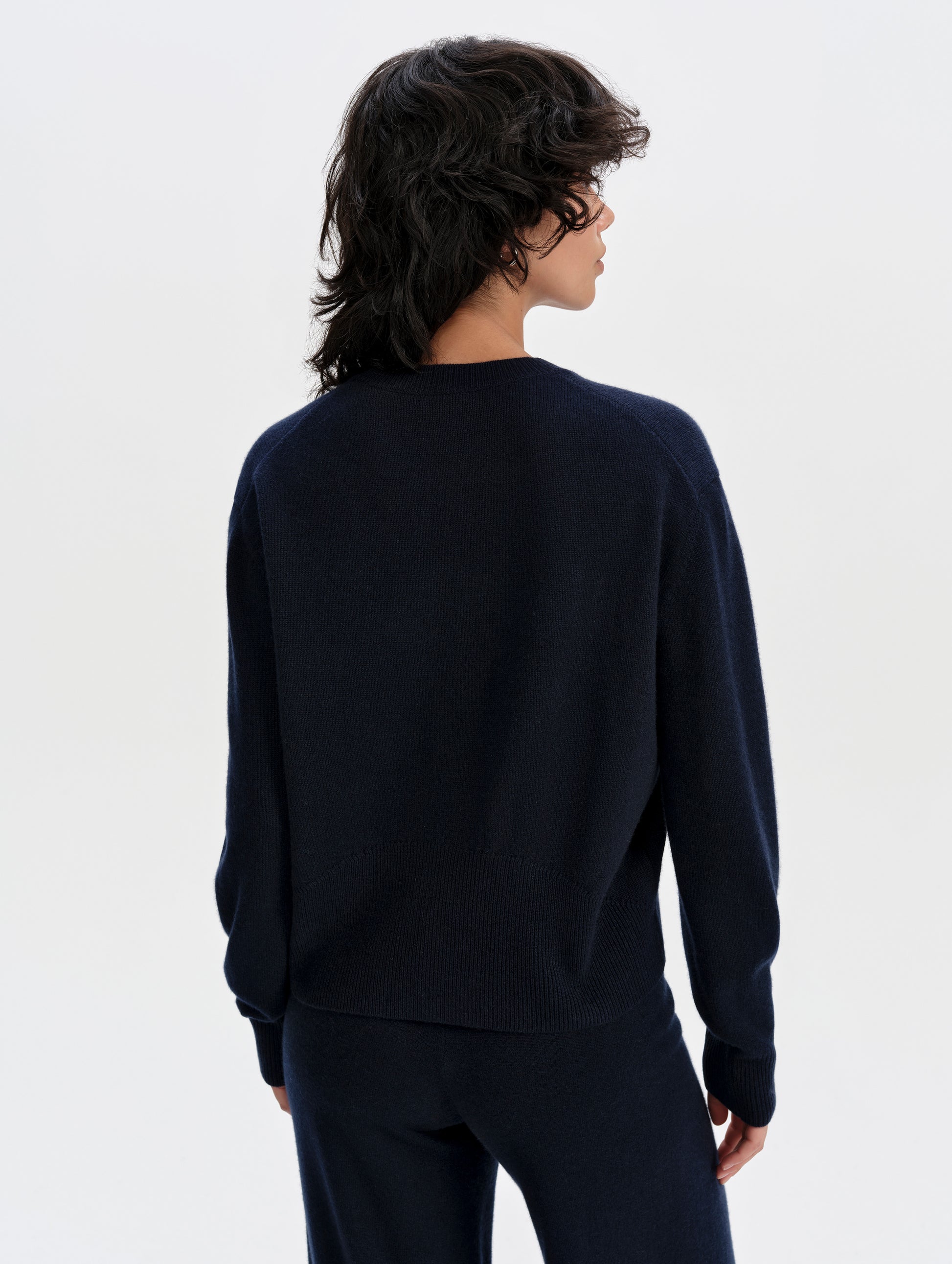 Rear upper-body view of woman wearing the Solace Cashmere Sweater in Total Eclipse from AETHER Apparel.