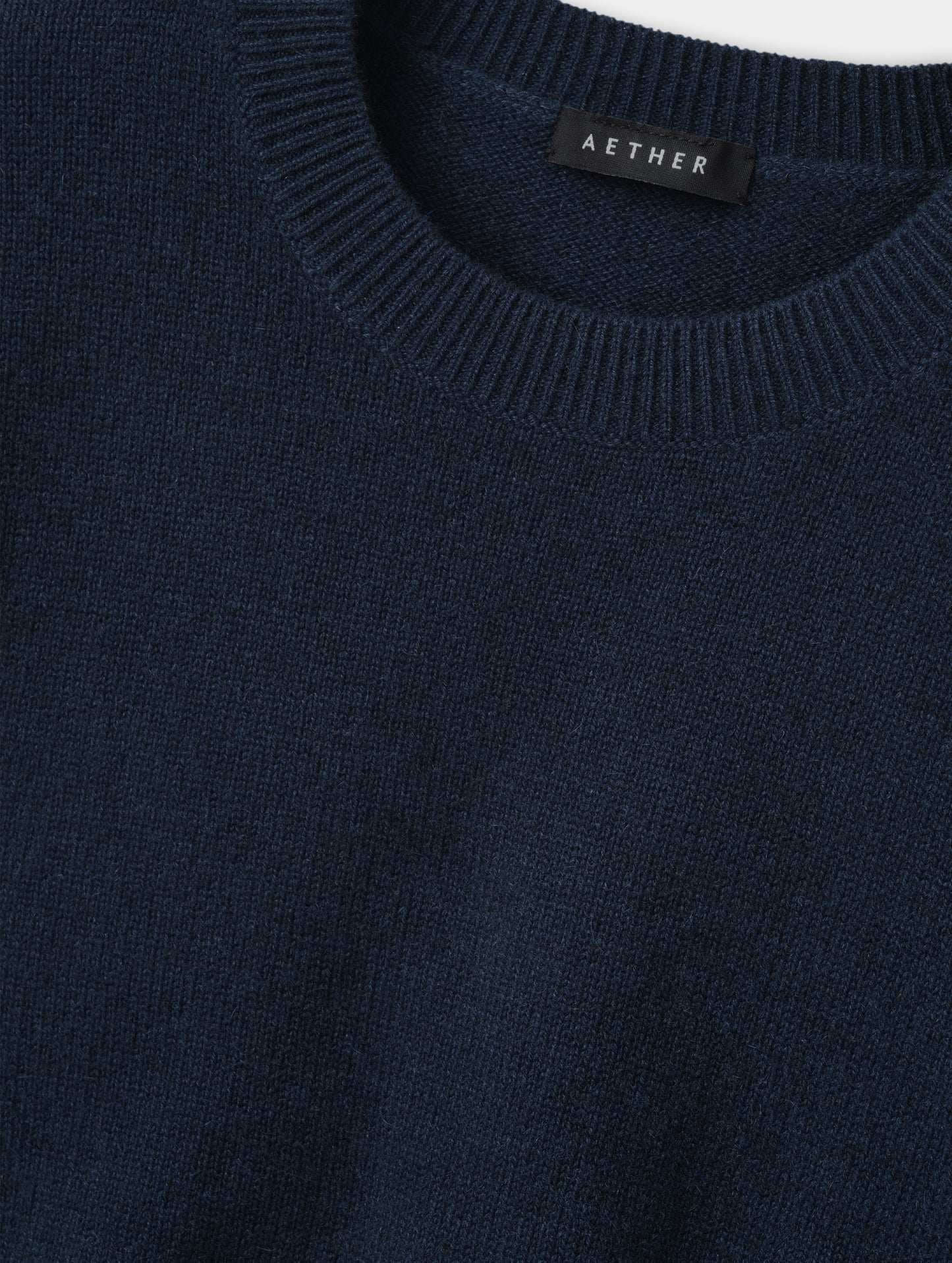 Closeup detailed view of the rib-knit collar and main body construction on the Solace Cashmere Sweater in Total Eclipse from AETHER Apparel.