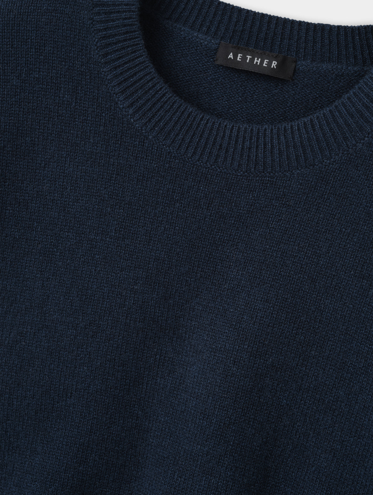 Closeup detailed view of the rib-knit collar and main body construction on the Solace Cashmere Sweater in Total Eclipse from AETHER Apparel.