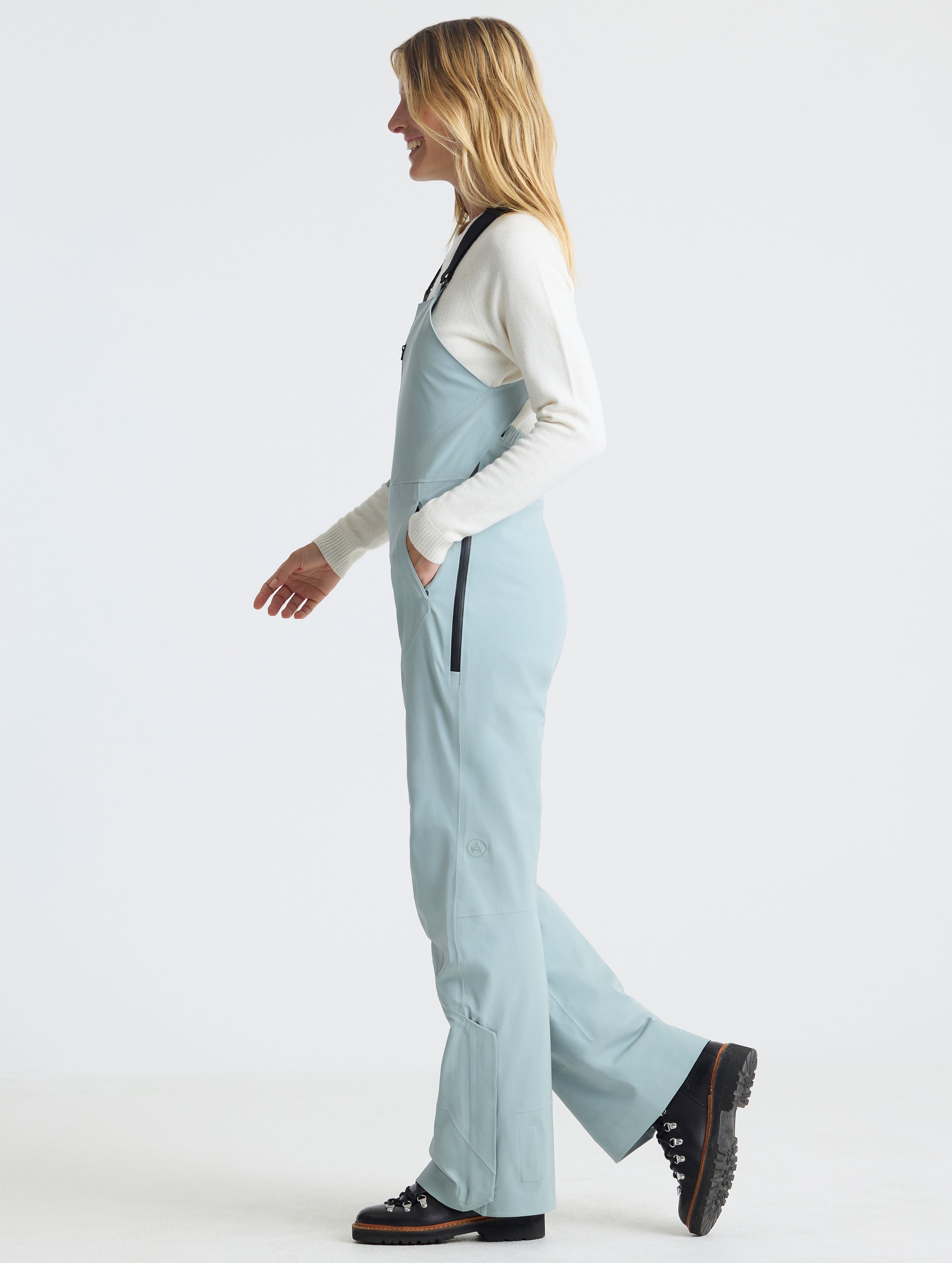 Side profile full-body view of woman wearing the Sophia Insulated Snow Bib in Jadewood Green from AETHER Apparel.