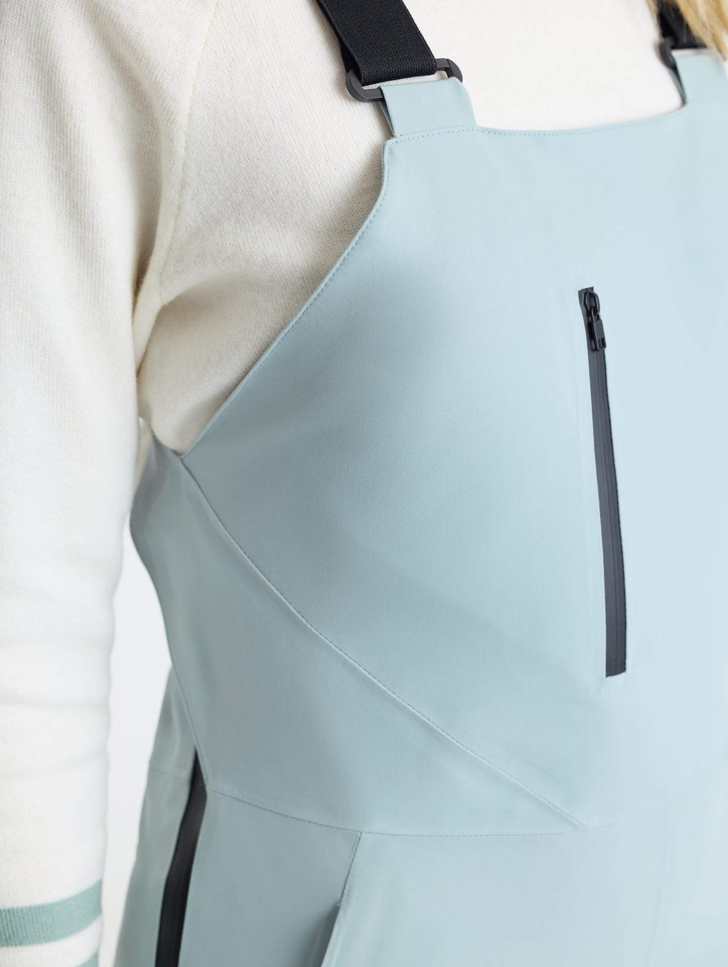 Closeup detailed view of the zipper-secured vertical chest pocket on the Sophia Insulated Snow Bib in Jadewood Green from AETHER Apparel.
