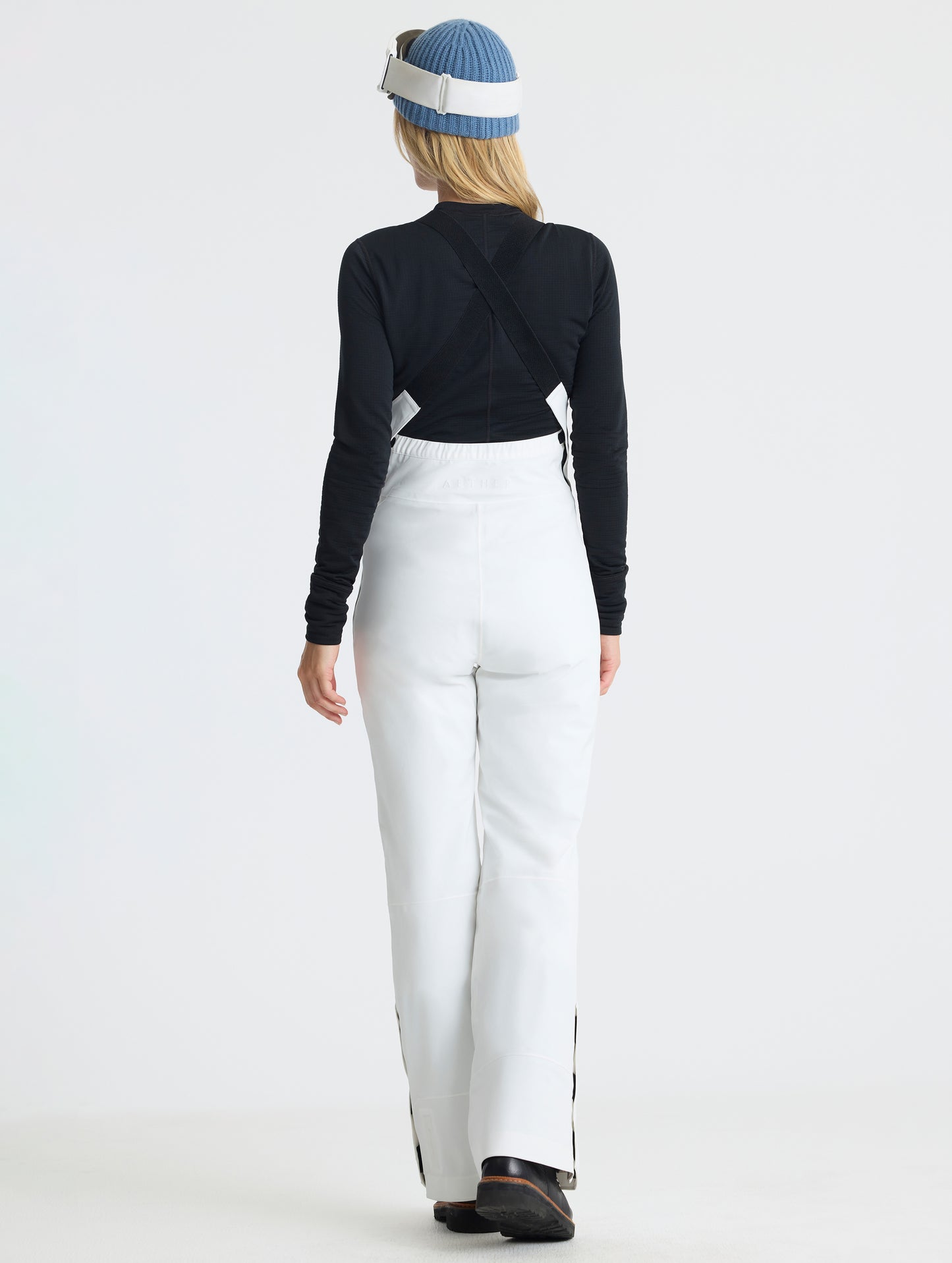 Rear full-body view of woman wearing the Sophia Insulated Snow Bib in Winter White from AETHER Apparel.