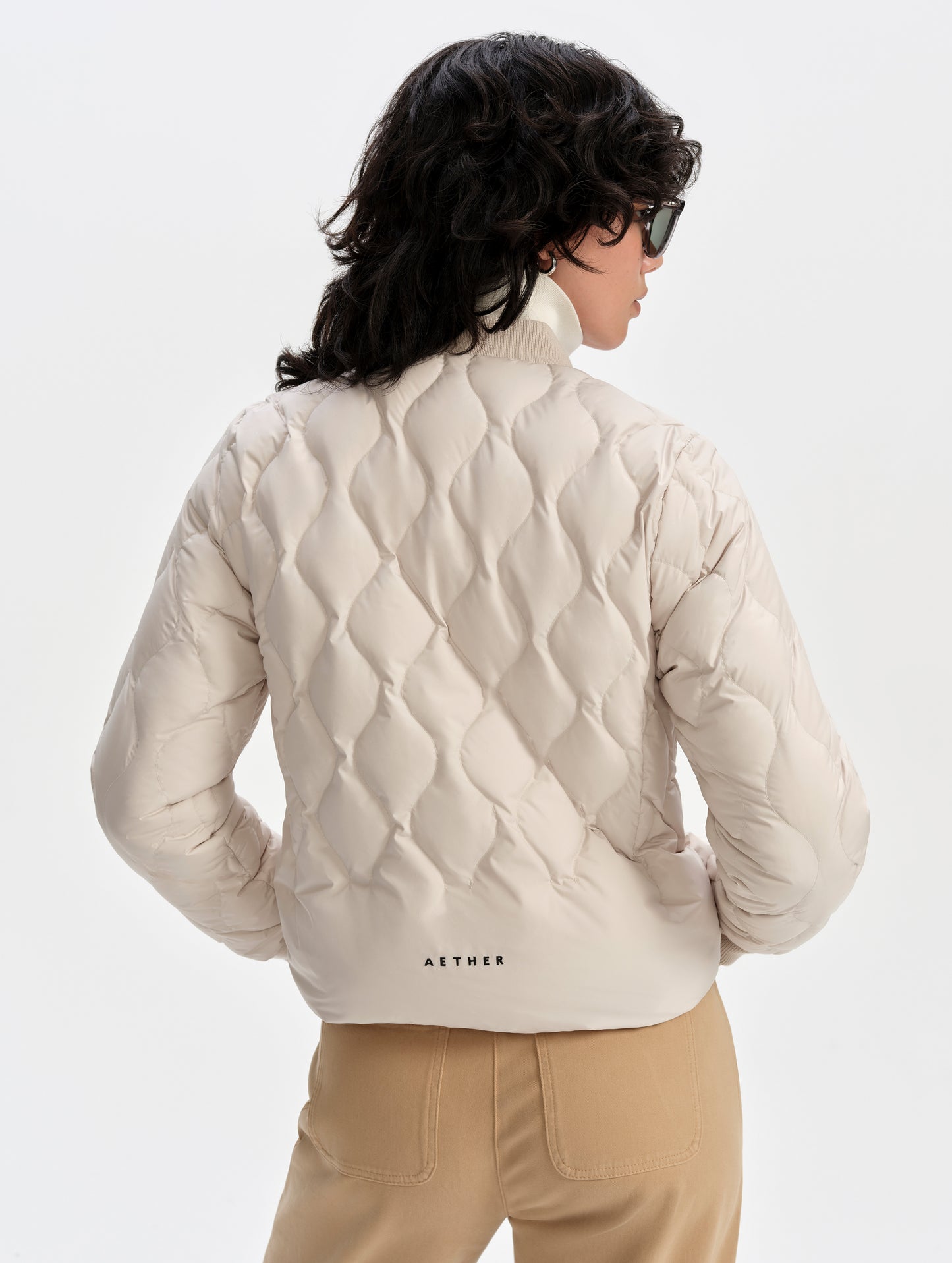 Rear upper-body view of woman wearing the Stella Liner Jacket in Bone from AETHER Apparel.