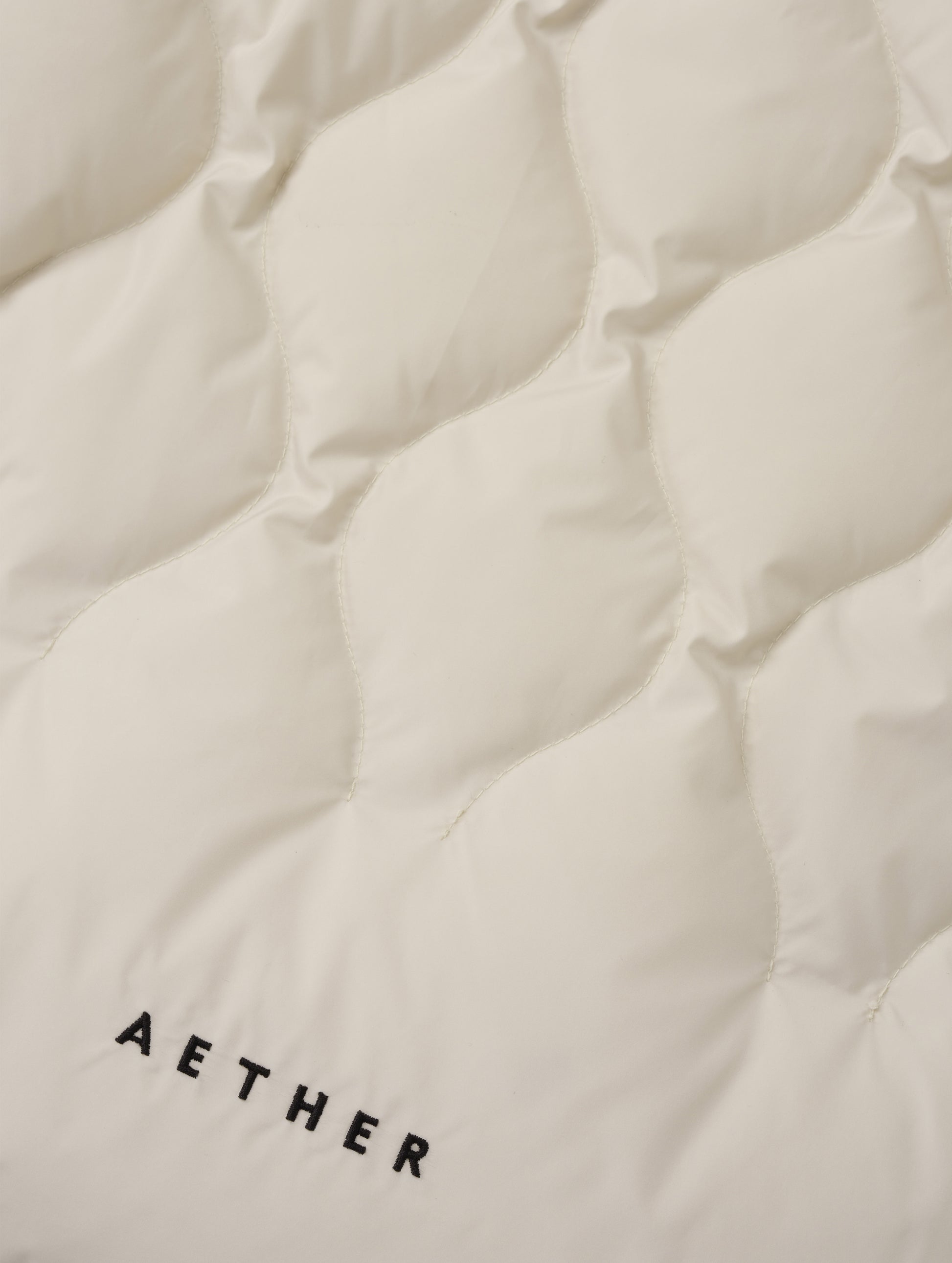 Closeup detailed view of the custom quilted pattern on the Stella Liner Jacket in Bone from AETHER Apparel with center-front closed. 