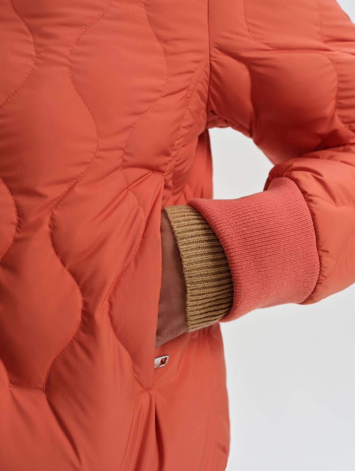 Closeup detailed view of the sleeve cuffs and hand pockets on the Stella Liner Jacket in Madeira Orange from AETHER Apparel.