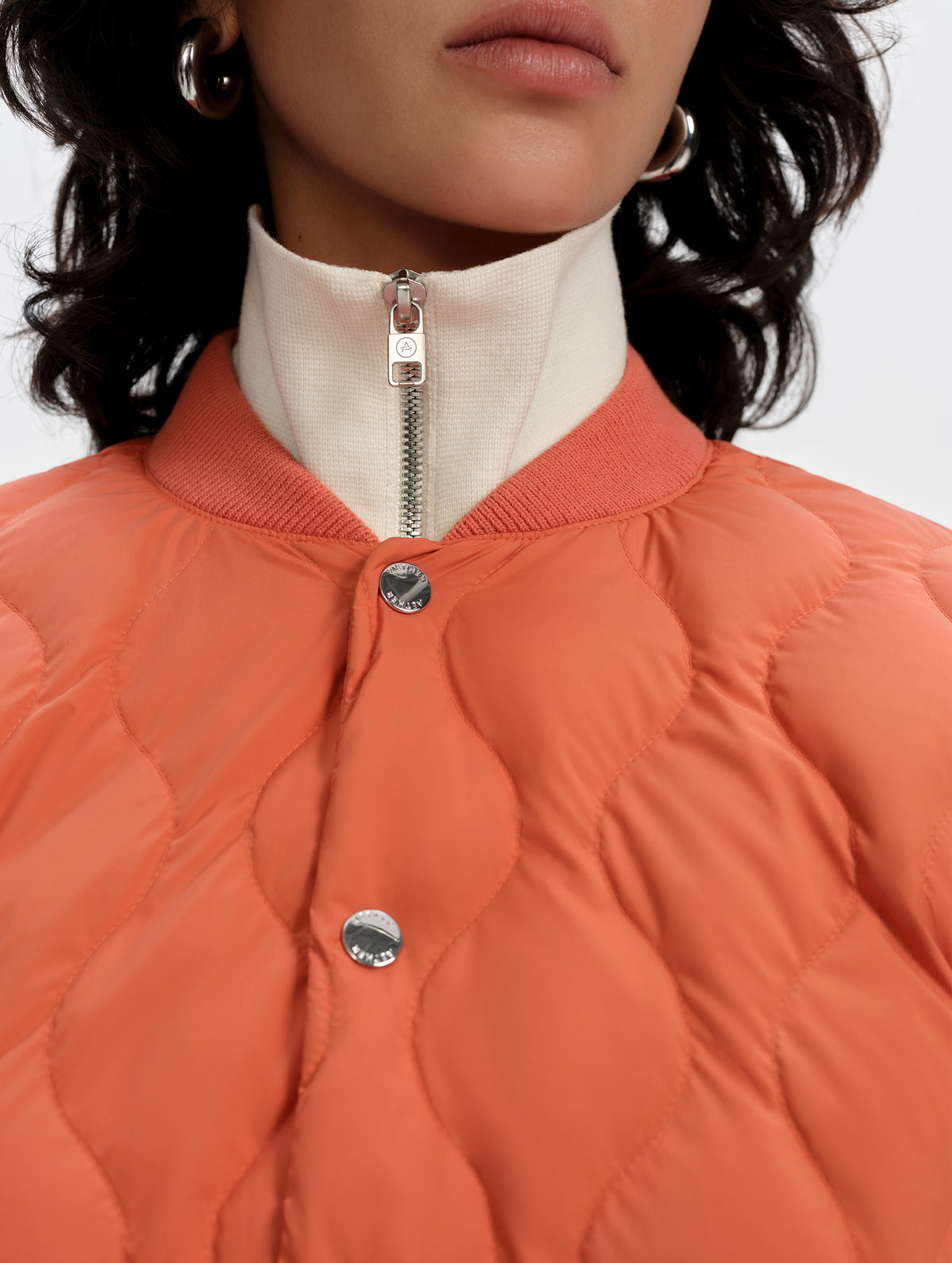 Closeup detailed view of the collar and custom AETHER snap buttons on the Stella Liner Jacket in Madeira Orange from AETHER Apparel.
