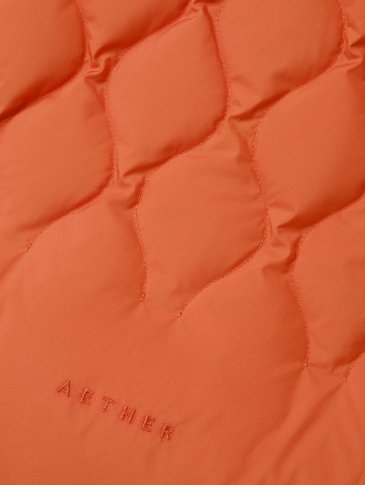 Closeup detailed view of the custom quilted pattern on the Stella Liner Jacket in Madeira Orange from AETHER Apparel with center-front closed. 