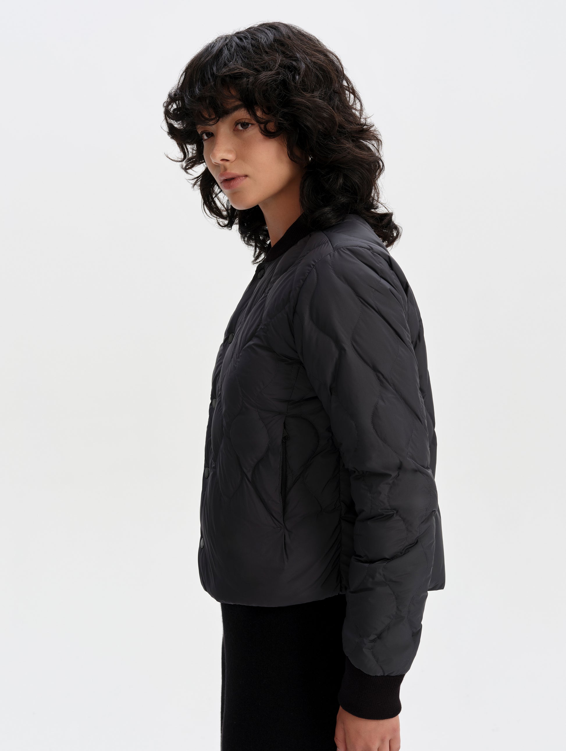 Side profile upper-body view of woman wearing the Stella Liner Jacket in Onyx Black from AETHER Apparel.