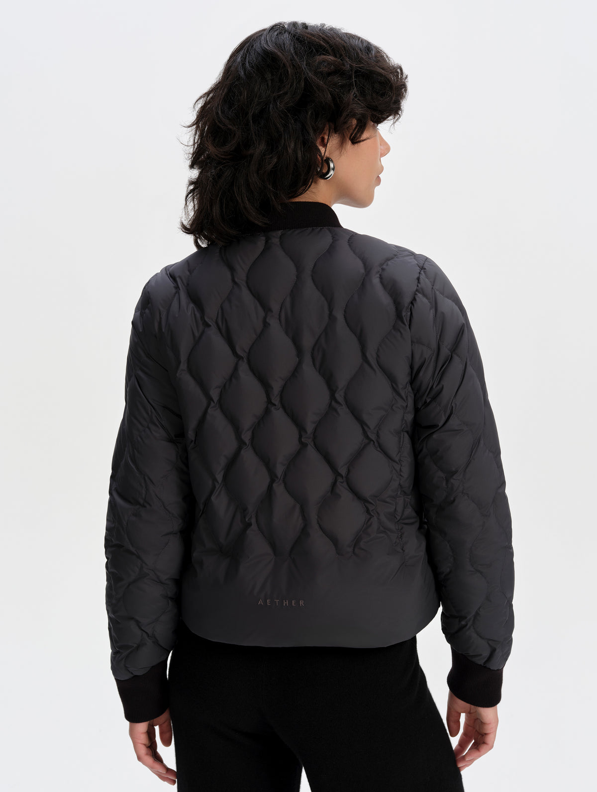 Rear upper-body view of woman wearing the Stella Liner Jacket in Onyx Black from AETHER Apparel.