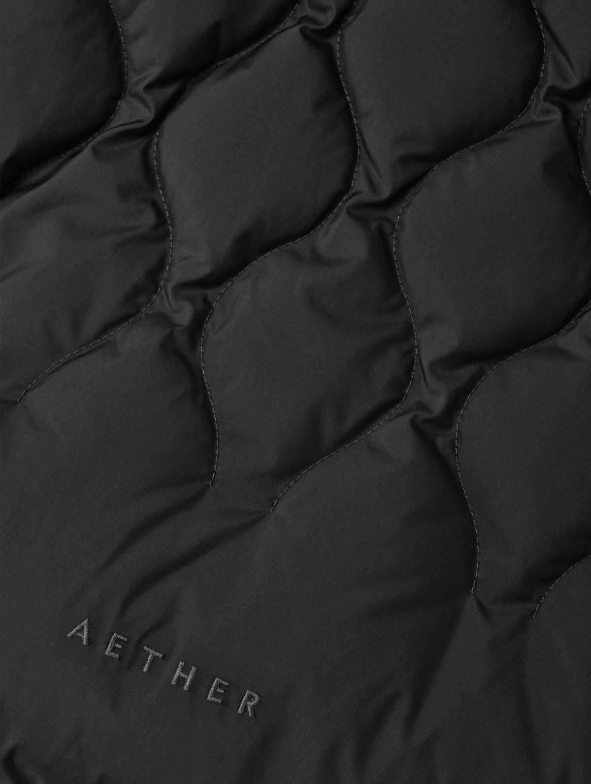 Closeup detailed view of the custom quilted pattern on the Stella Liner Jacket in Onyx Black from AETHER Apparel with center-front closed. 