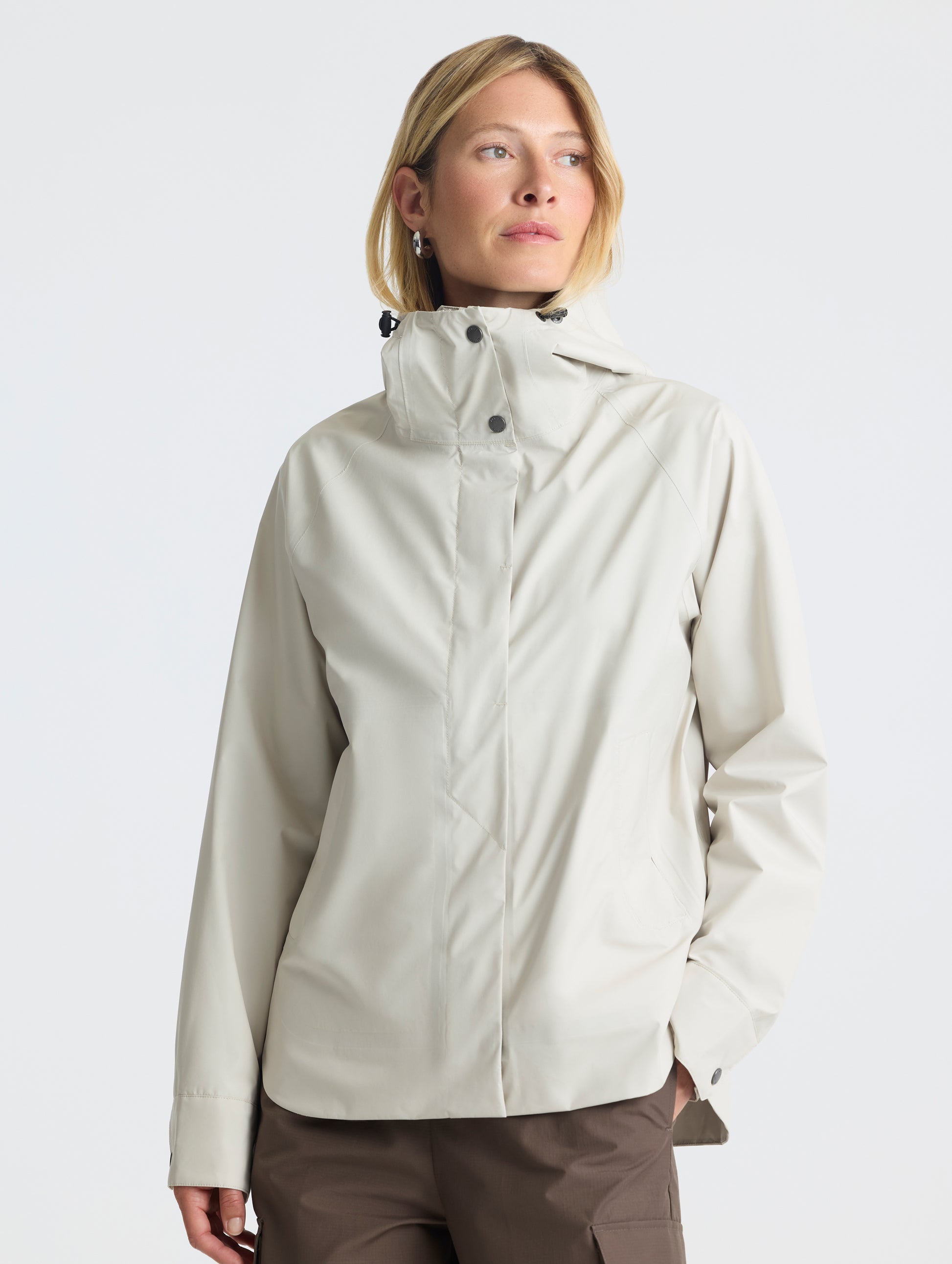 Front view of woman wearing Storm All-Weather Jacket in Bone white from AETHER Apparel.
