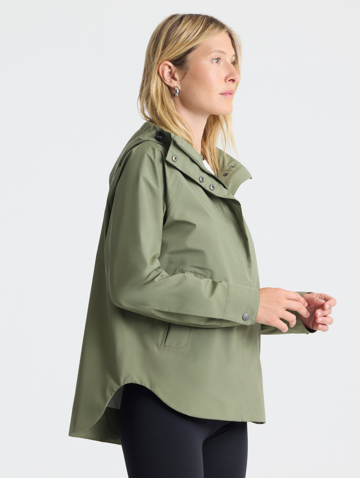 Right-angled view of woman wearing Storm All-Weather Jacket in Fern Green from AETHER Apparel.