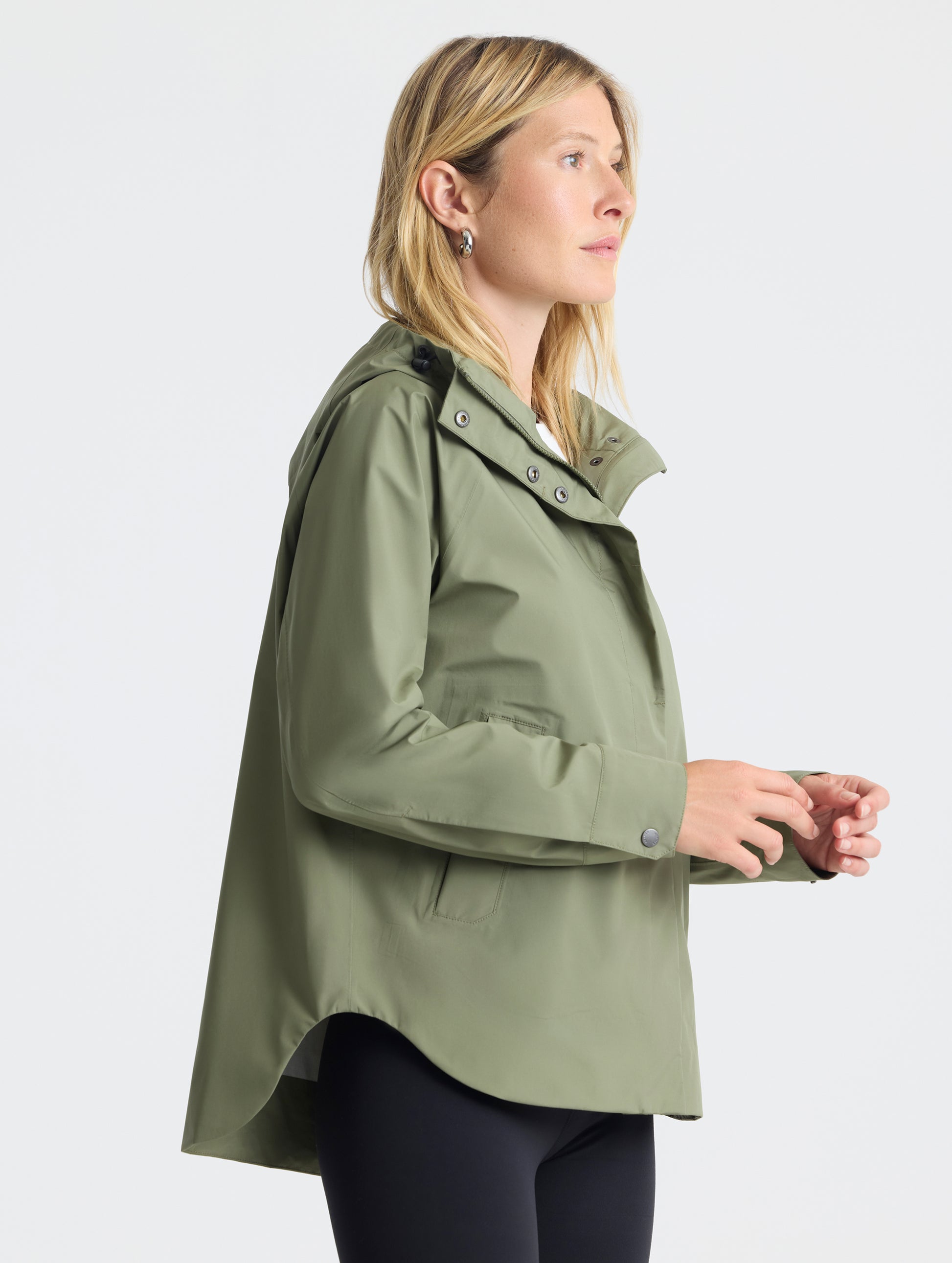 Right-angled view of woman wearing Storm All-Weather Jacket in Fern Green from AETHER Apparel.