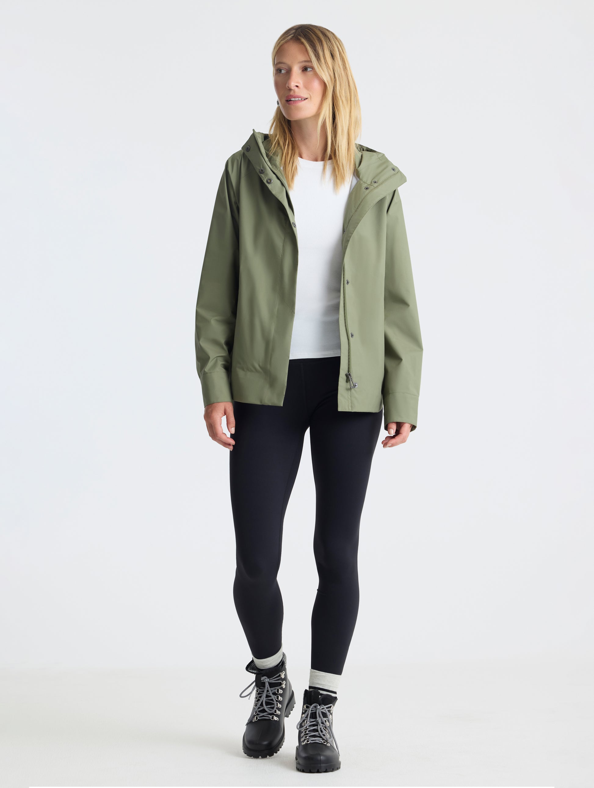 Full body view of woman wearing Storm All-Weather Jacket in Fern Green from AETHER Apparel.