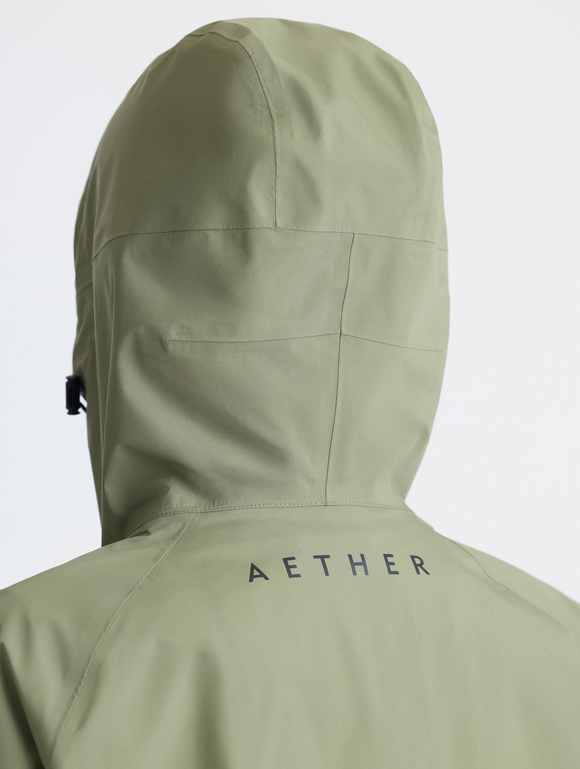 Rear closeup view of woman wearing hood of Storm All-Weather Jacket in Fern Green from AETHER Apparel.