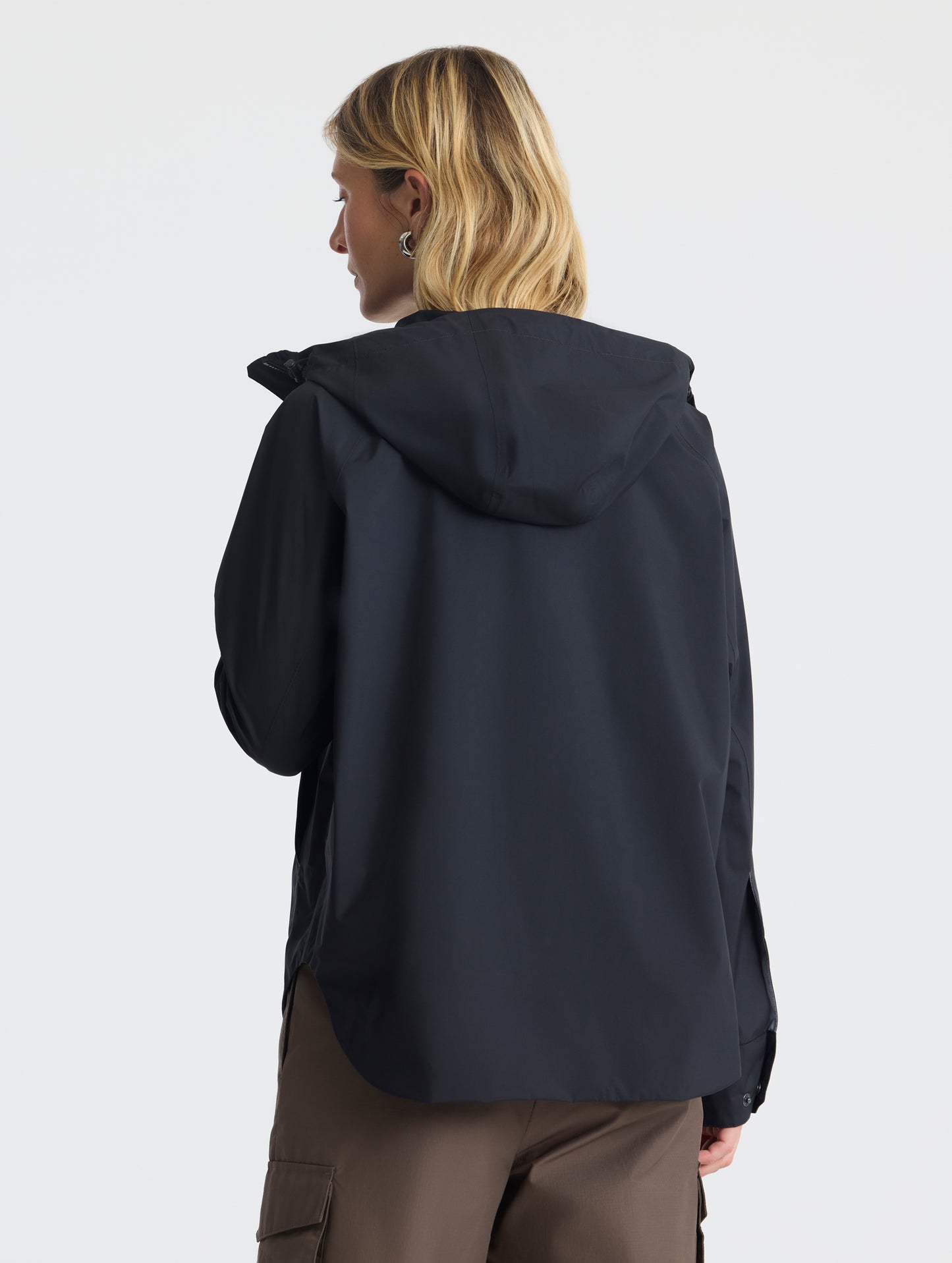 Rear view of woman wearing Storm All-Weather Jacket in Onyx Black from AETHER Apparel.