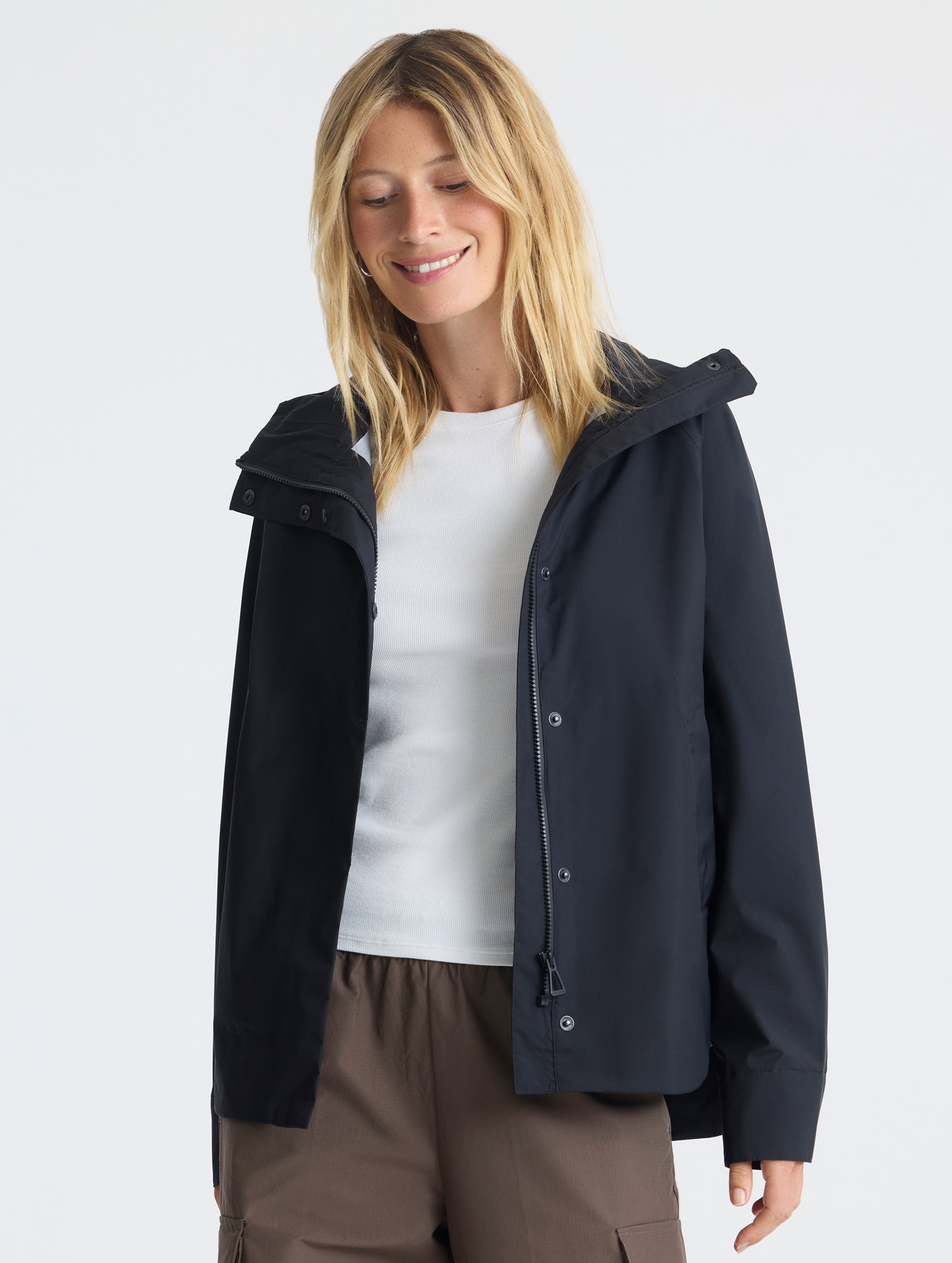 Front view of woman wearing unzipped Storm All-Weather Jacket in Onyx Black from AETHER Apparel.
