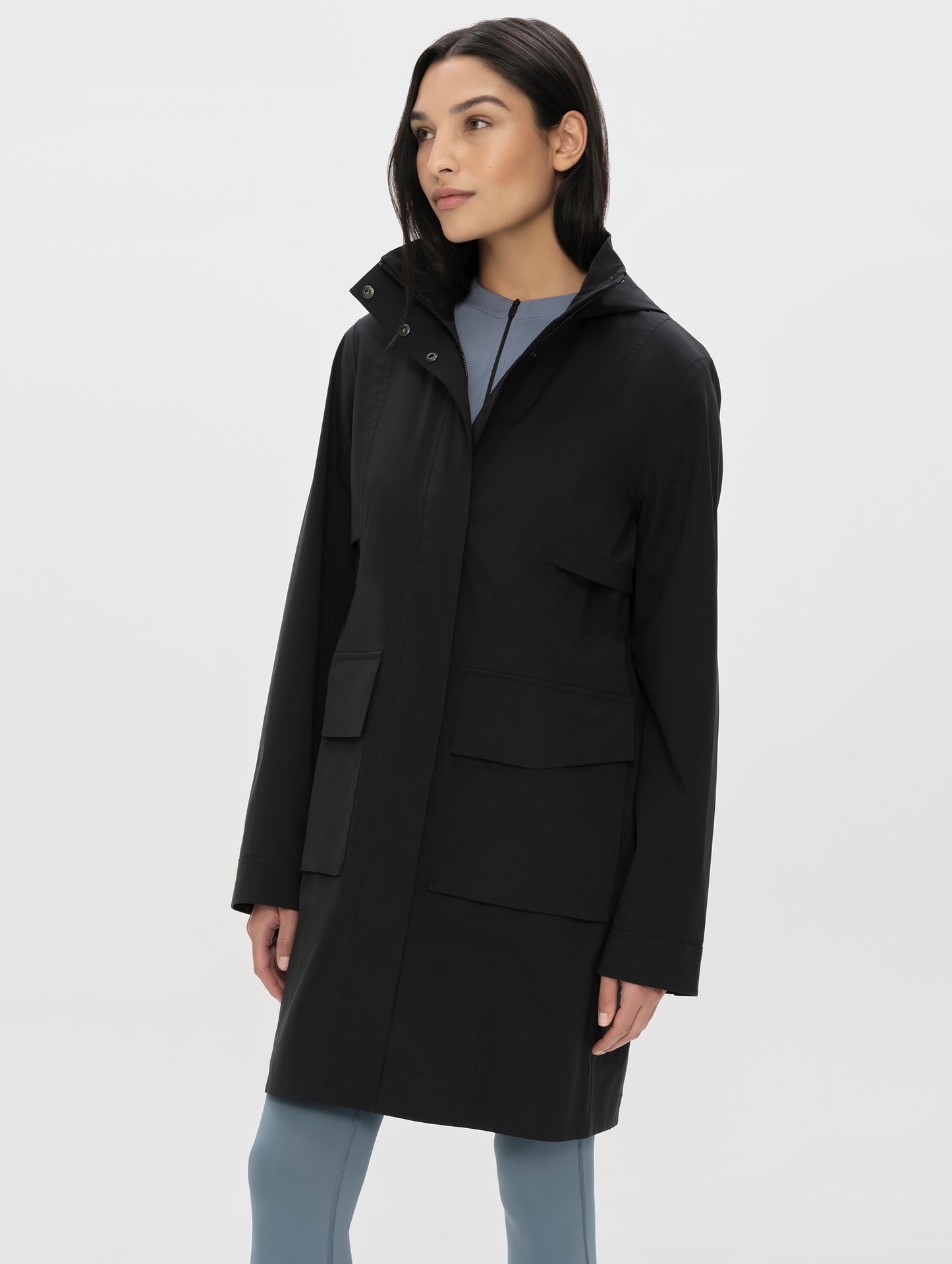 Front, angled, upper-body view of woman wearing the Wallace Rain Parka in Onyx Black from AETHER Apparel.