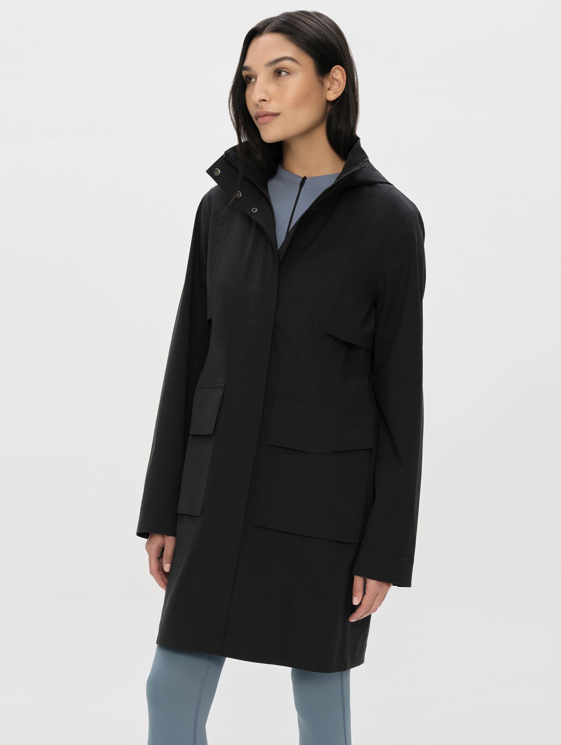 Front, angled, upper-body view of woman wearing the Wallace Rain Parka in Onyx Black from AETHER Apparel.