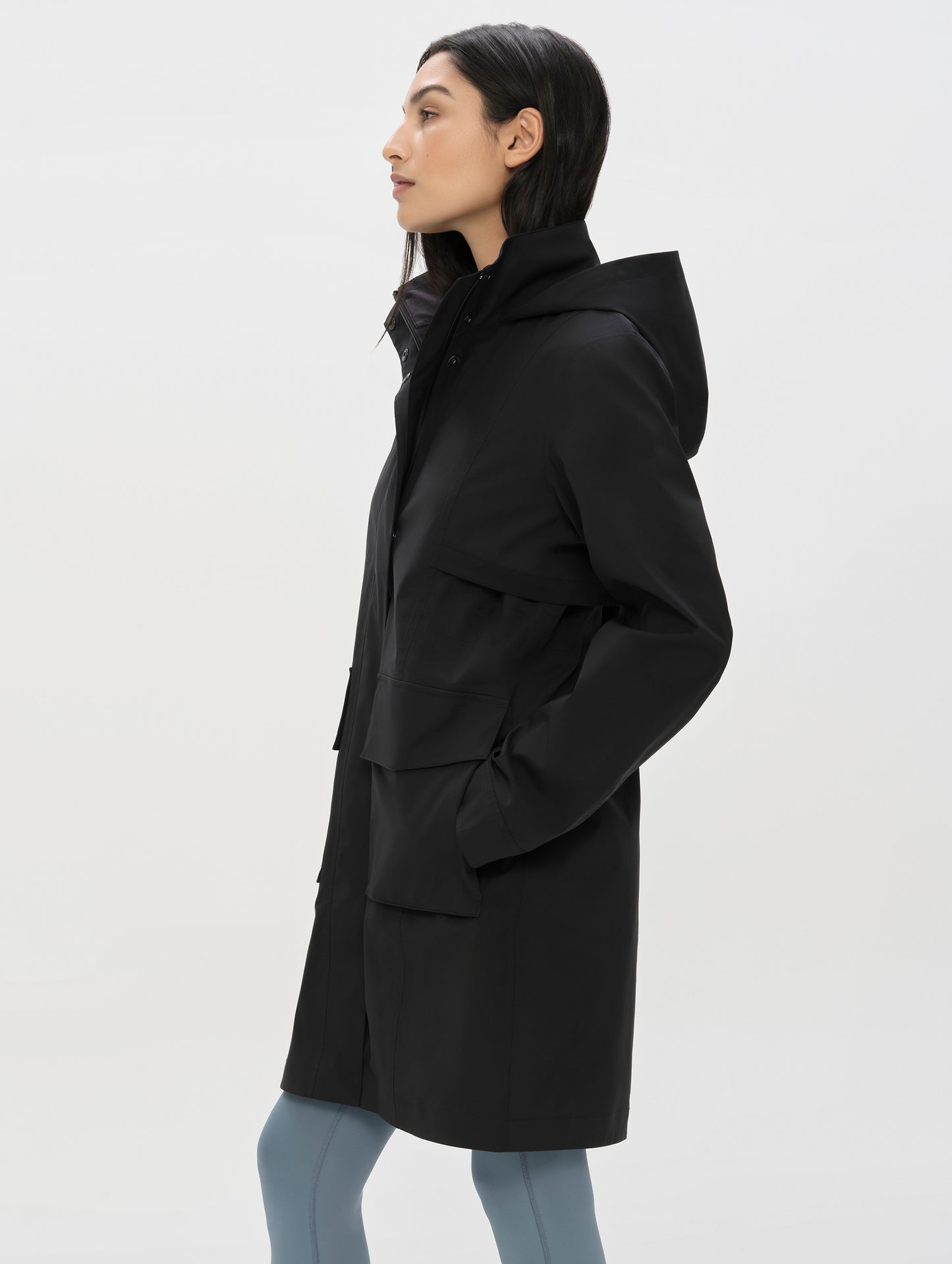 Side profile upper-body view of woman wearing the Wallace Rain Parka in Onyx Black from AETHER Apparel.