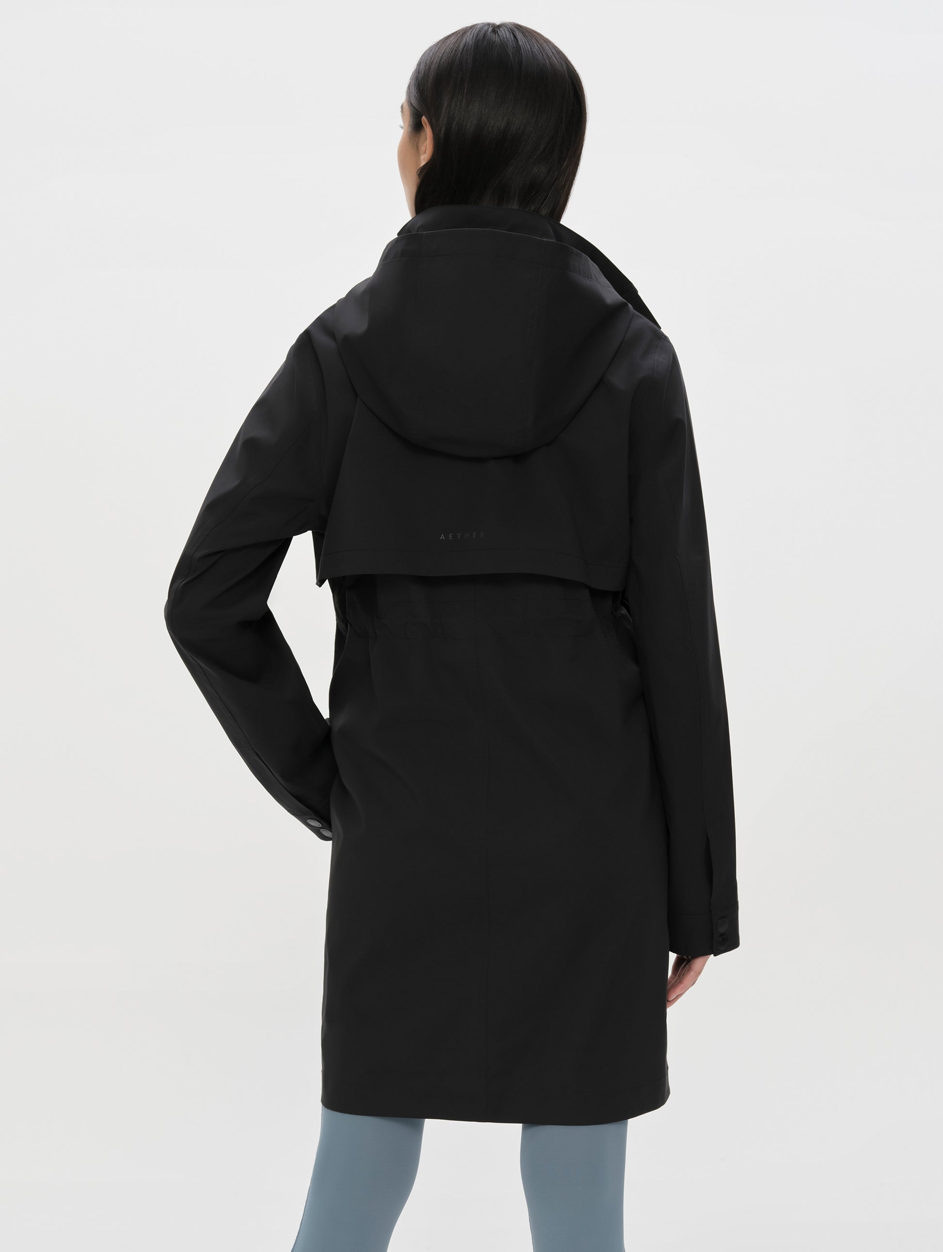 Rear upper-body view of woman wearing the Wallace Rain Parka in Onyx Black from AETHER Apparel.