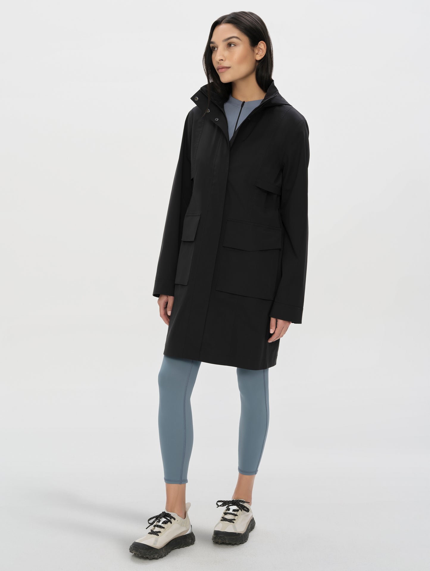 Front, angled full-body view of woman wearing the Wallace Rain Parka in Onyx Black from AETHER Apparel.