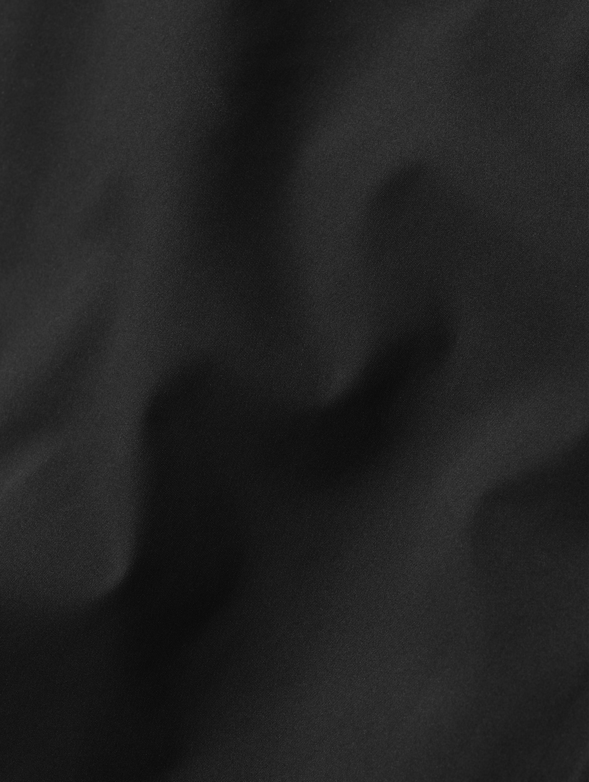 Closeup detailed view of the three-layer stretch fabric on the women's Wallace Rain Parka in Onyx Black from AETHER Apparel.