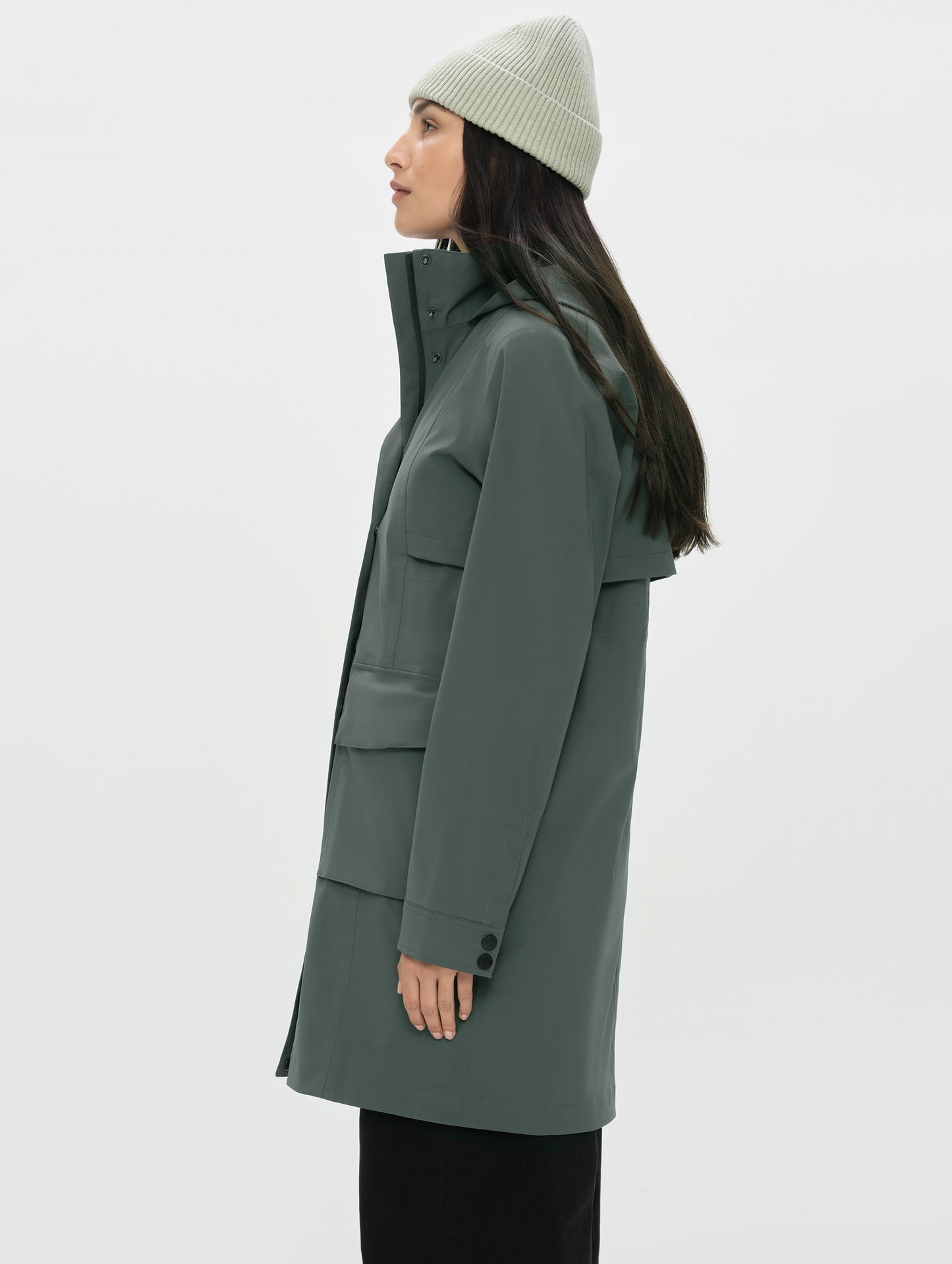 Side profile upper-body view of woman wearing the Wallace Rain Parka in Saville Green from AETHER Apparel.