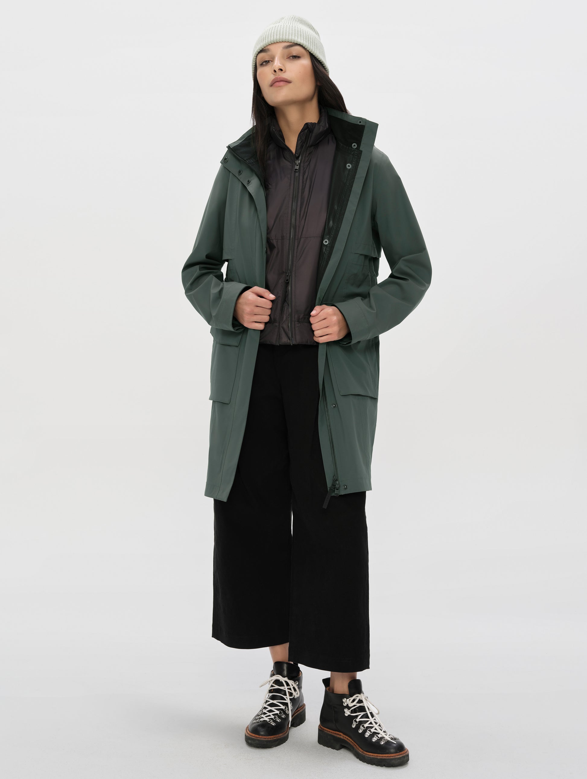 Front full-body view of woman wearing the unzipped Wallace Rain Parka in Saville Green from AETHER Apparel.