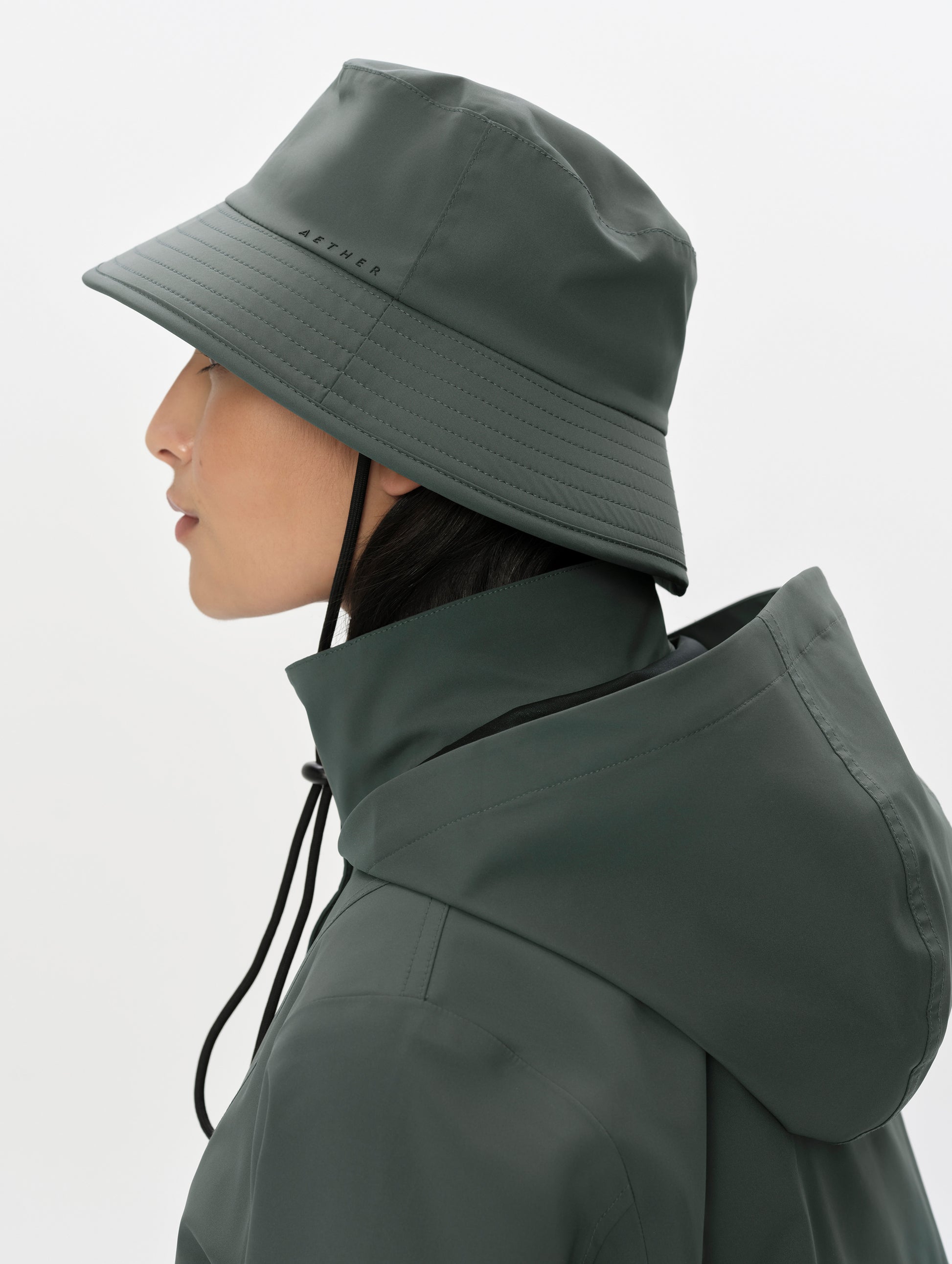 Side profile view of woman wearing the Wallace Bucket Hat in Saville Green from AETHER Apparel.