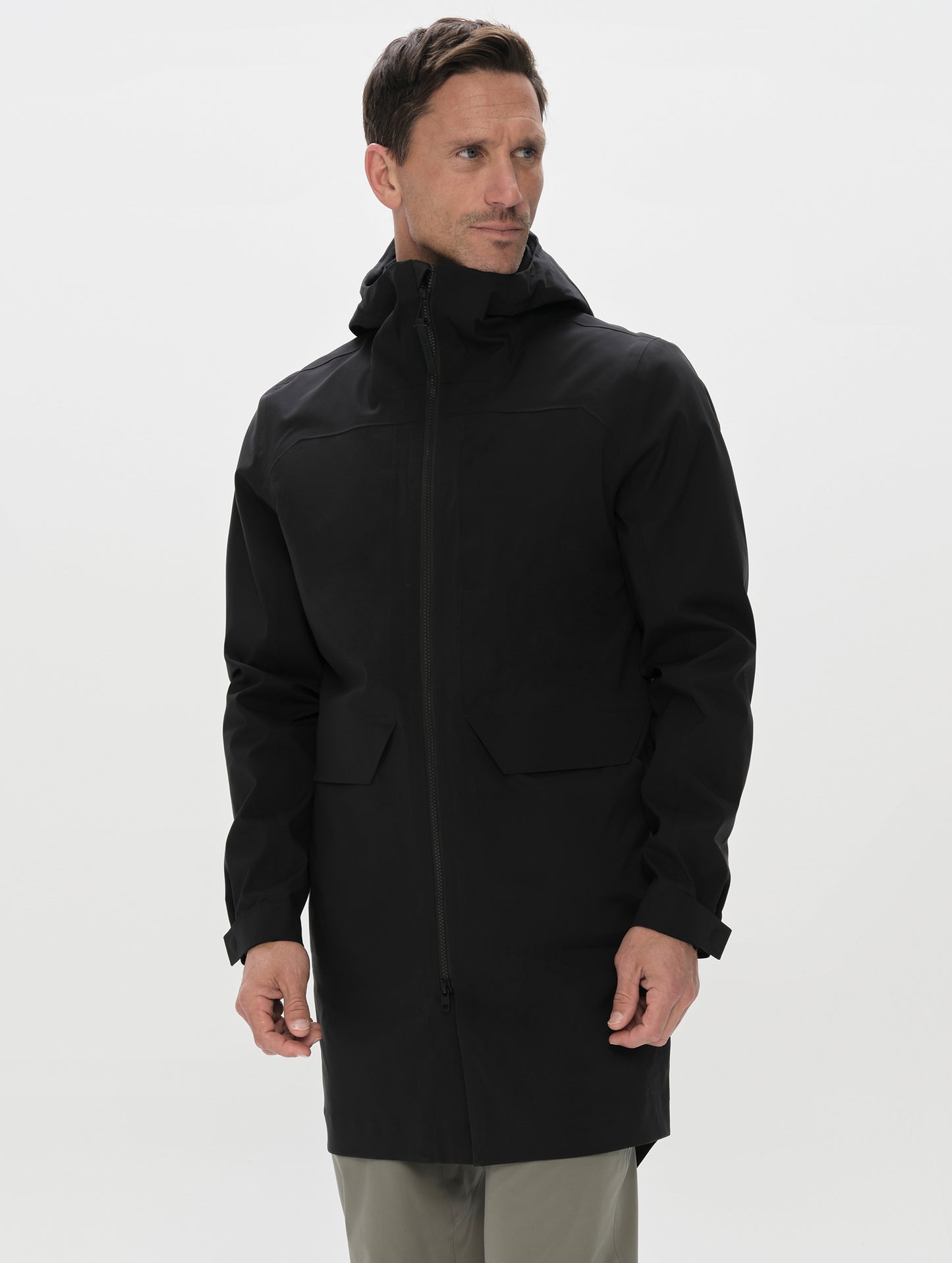 Front upper-body view of man wearing the Wallace Rain Parka in Onyx Black from AETHER Apparel with closed collar. 