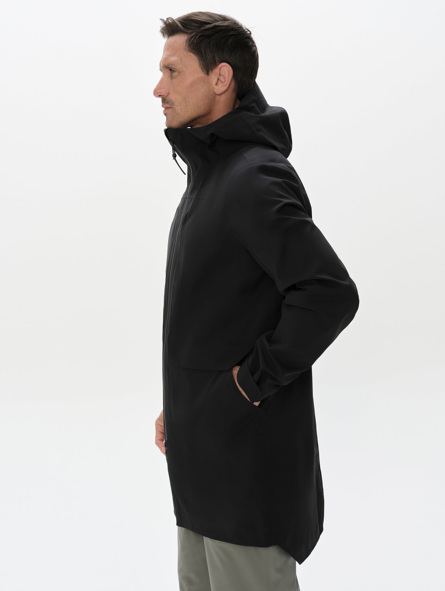 Side profile upper-body view of man wearing the Wallace Rain Parka in Onyx Black from AETHER Apparel.