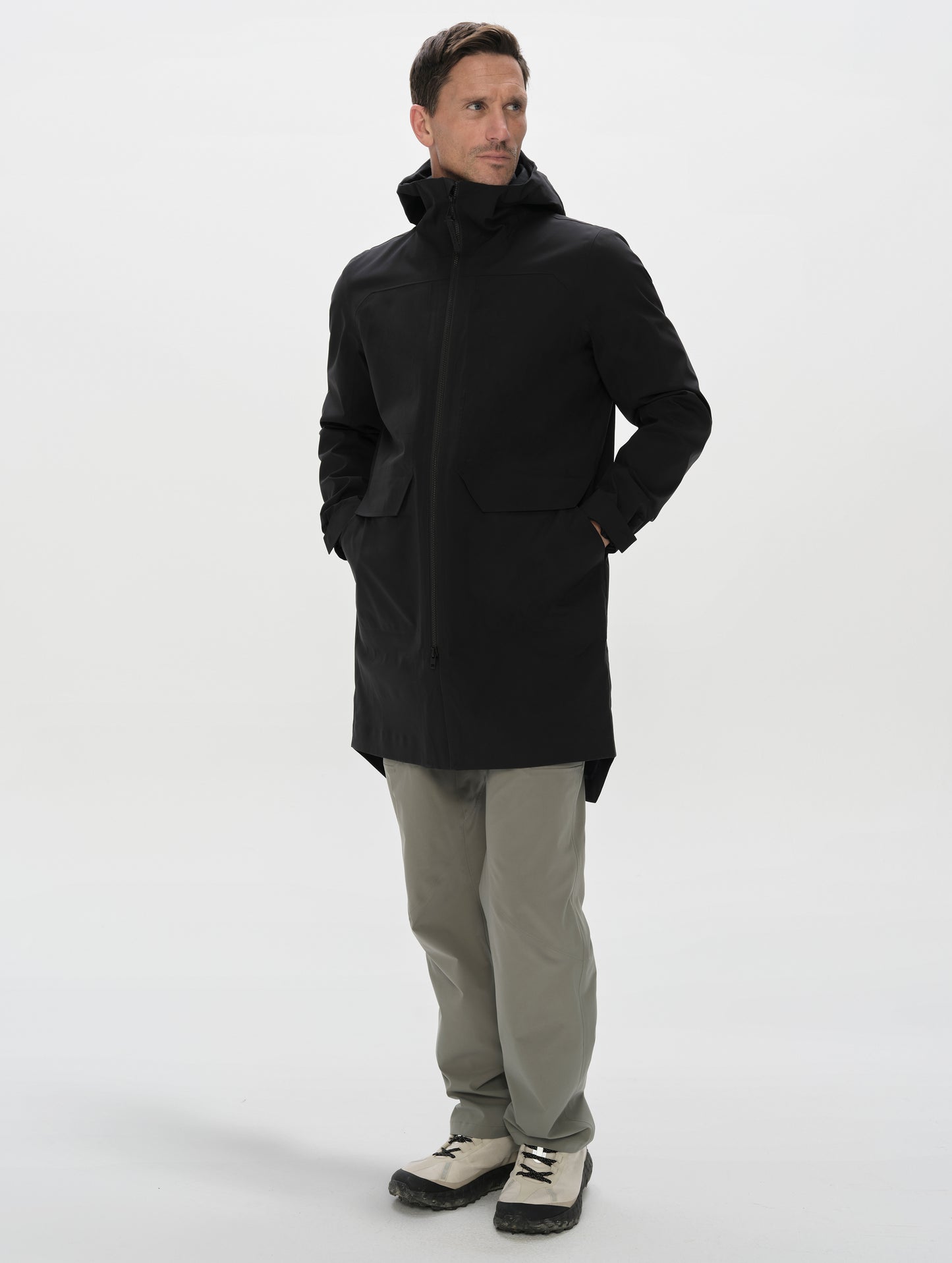 Full-body view of man wearing the Wallace Rain Parka in Onyx Black from AETHER Apparel unzipped.