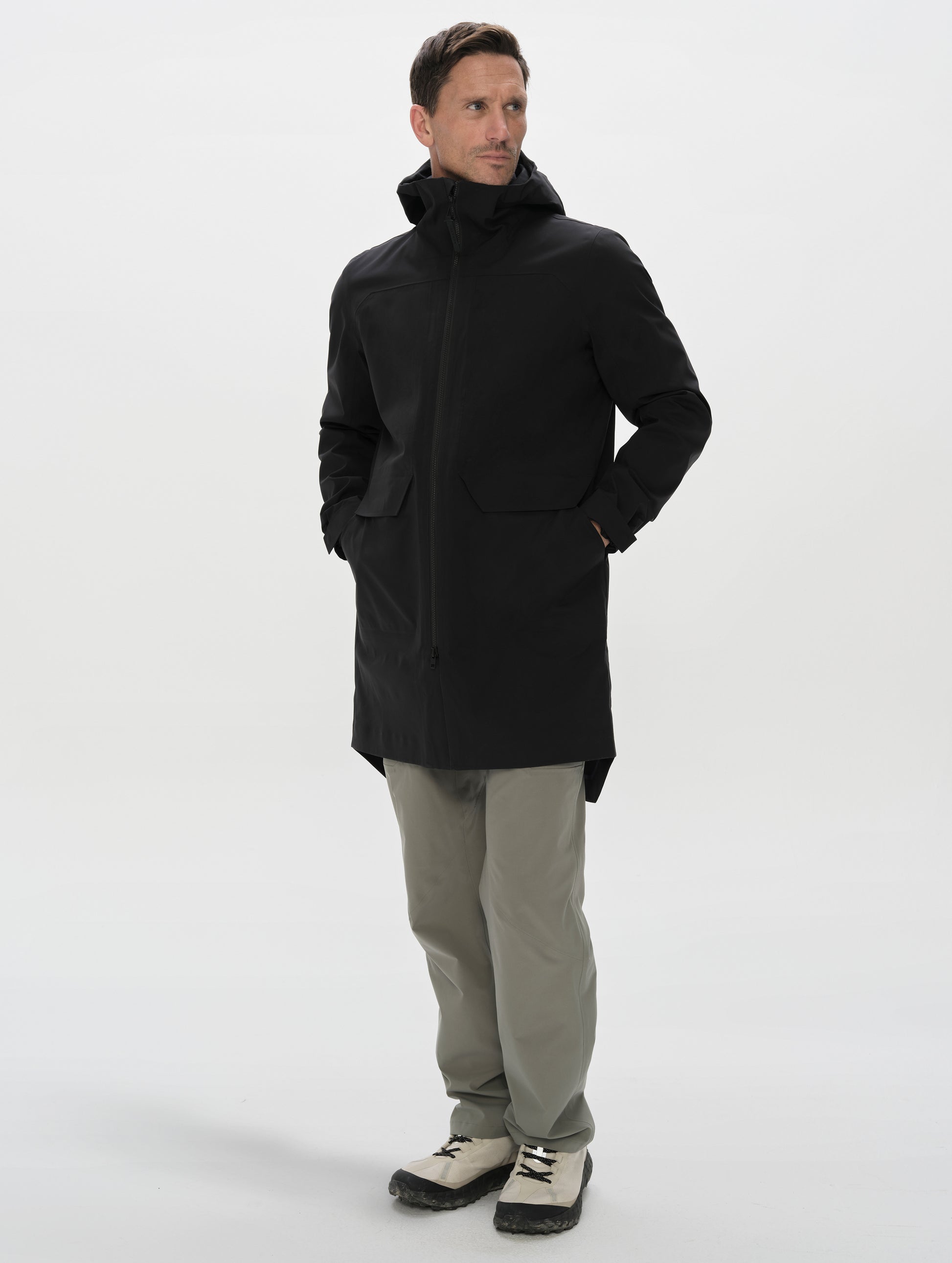 Full-body view of man wearing the Wallace Rain Parka in Onyx Black from AETHER Apparel unzipped.