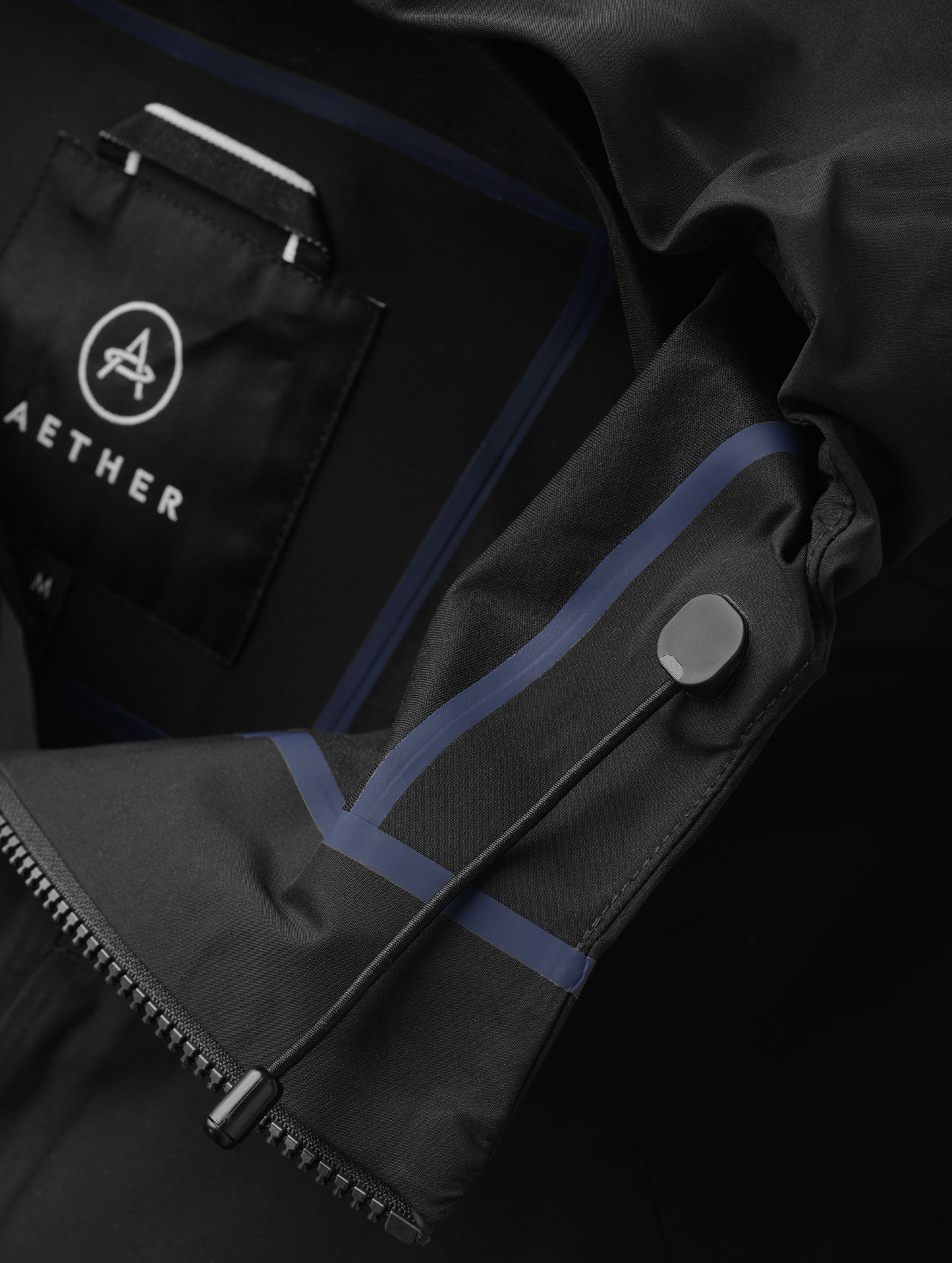 Closeup detailed view of the bungee system on the hood of the men's Wallace Rain Parka in Onyx Black from AETHER Apparel.