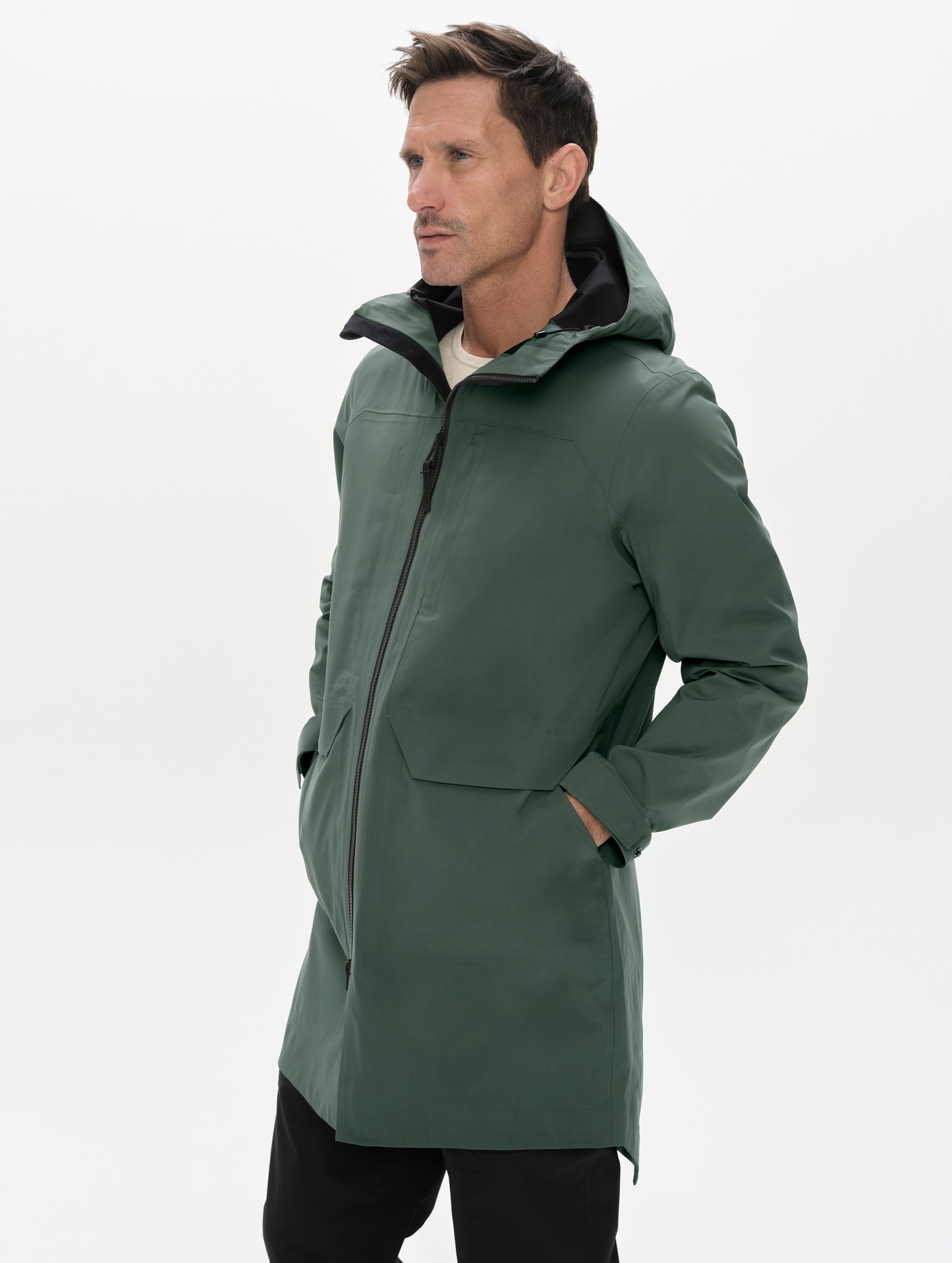 Front angled upper-body view of man wearing the Wallace Rain Parka in Saville Green from AETHER Apparel.