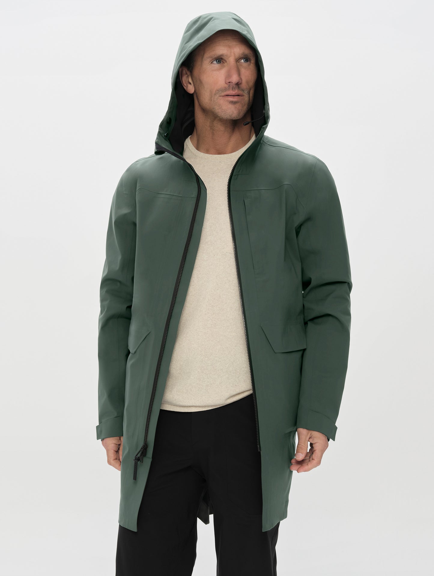 Front upper-body view of man wearing the Wallace Rain Parka in Saville Green from AETHER Apparel unzipped. 