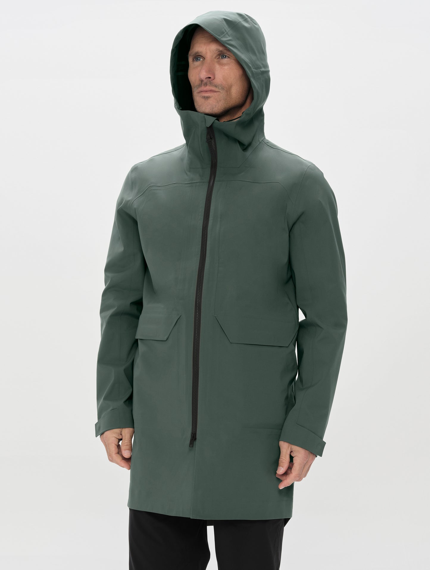 Front upper-body view of man wearing the Wallace Rain Parka in Saville Green from AETHER Apparel zipped up. 